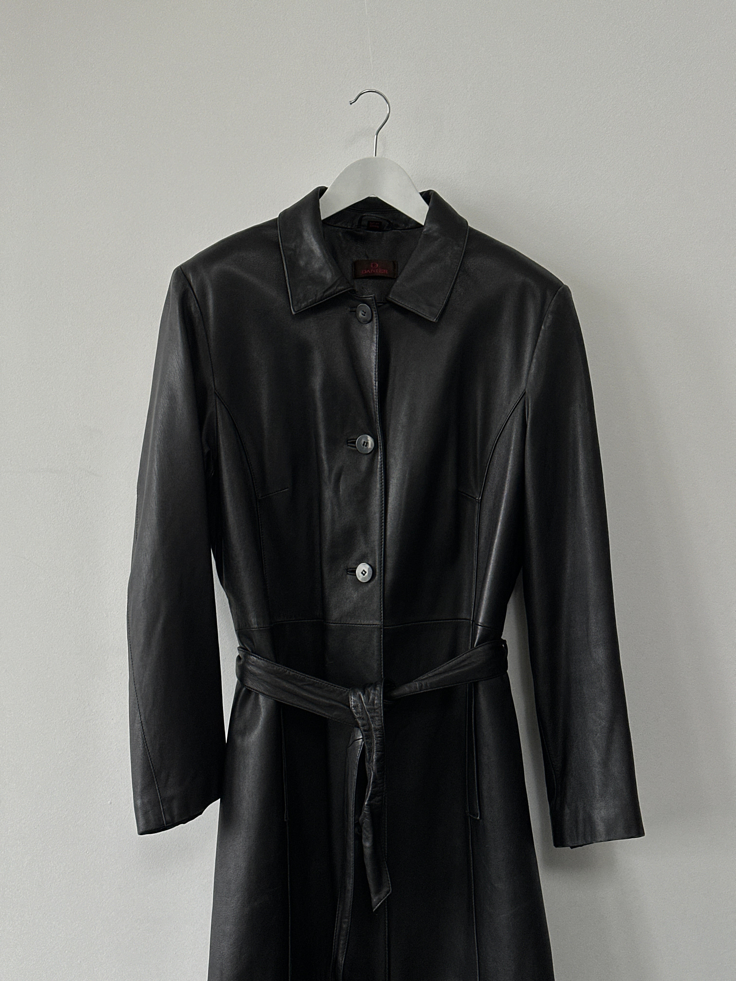 Vintage brand vintage leather trench coat with a belt, full-length floor style in XL size, shown hanging on a clothing rack.