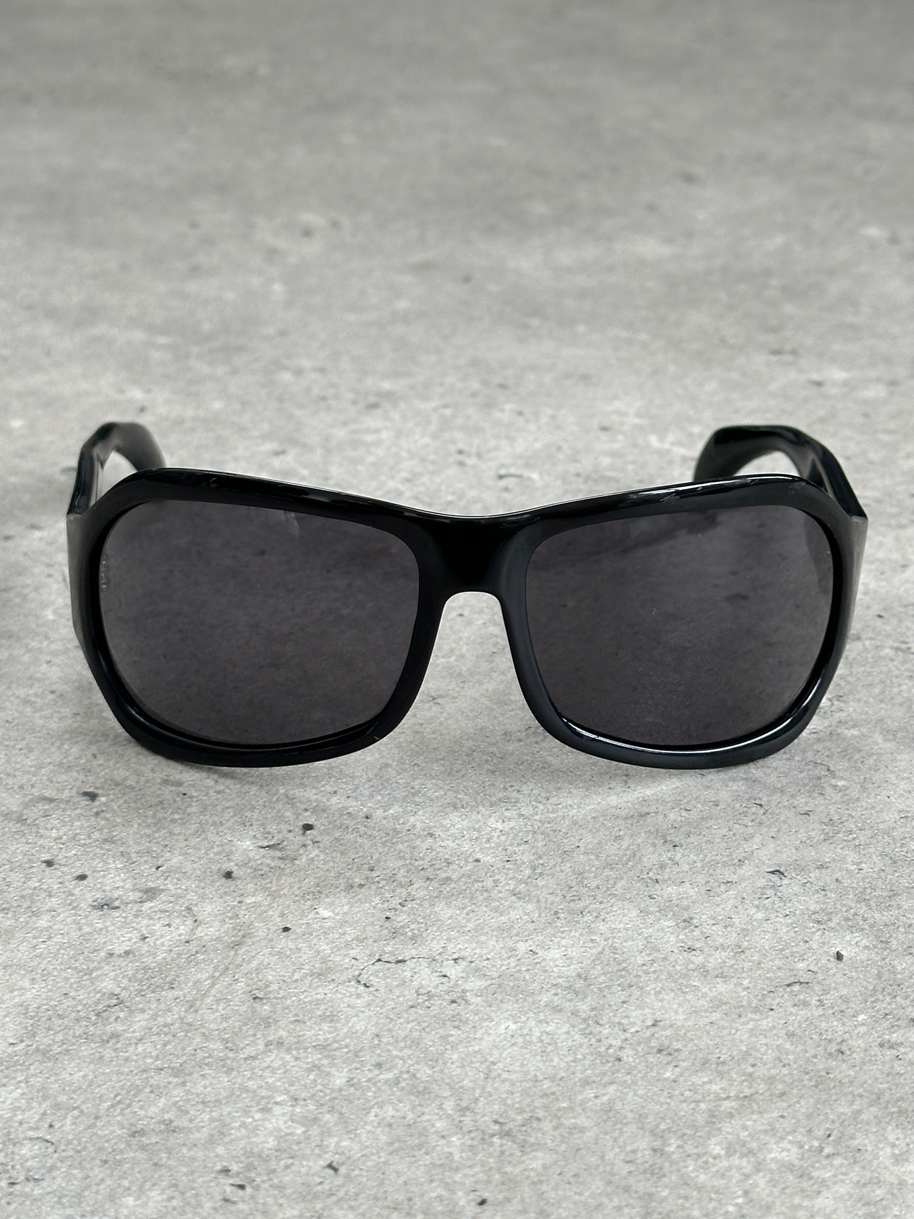 Vintage 2000s oversized shield sunglasses with bold black frames and dark lenses, featuring a distinctive vintage style.