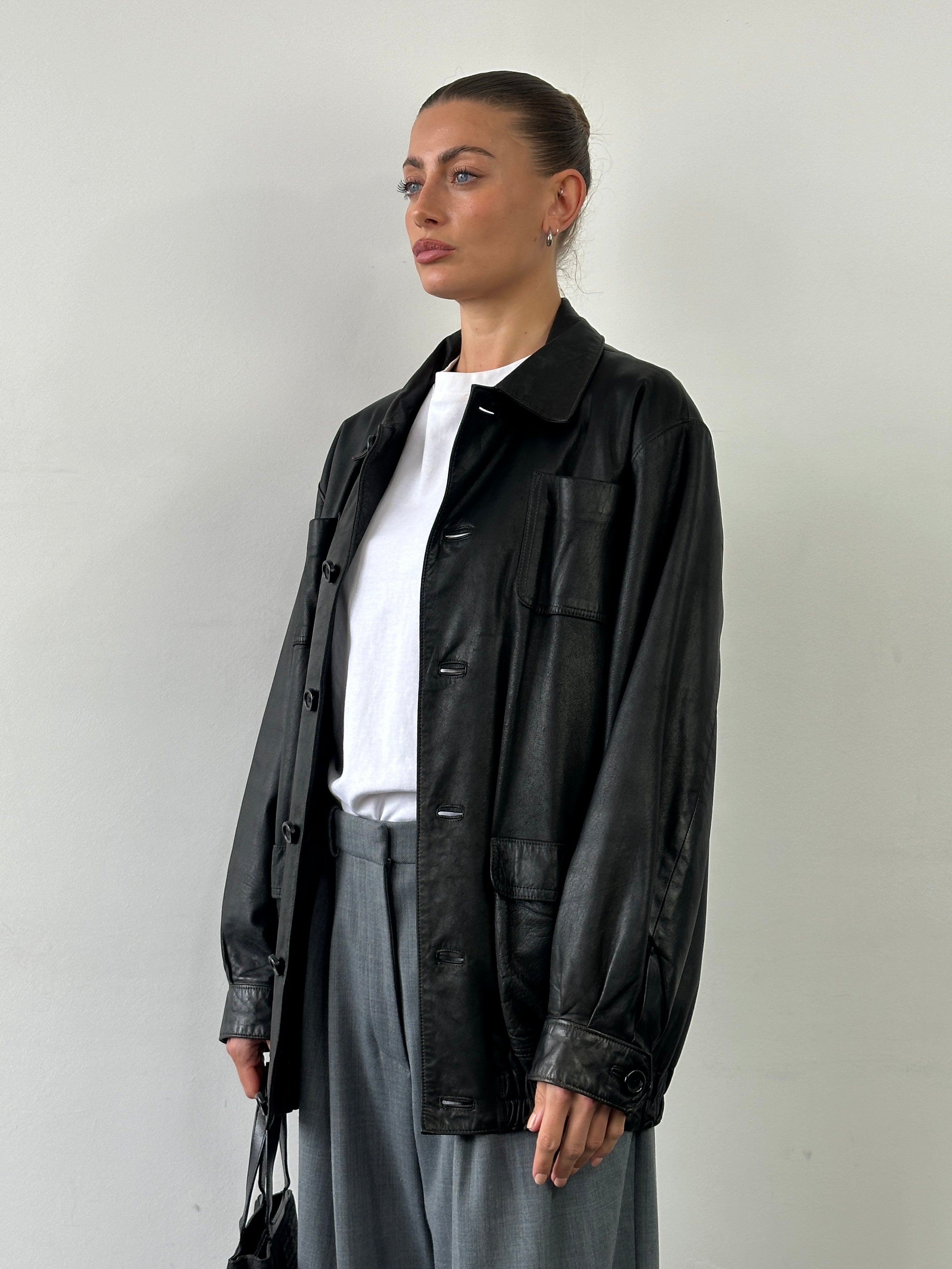 Vintage leather minimal bomber jacket in XL displayed on a hanger, showcasing its classic design and smooth leather texture.
