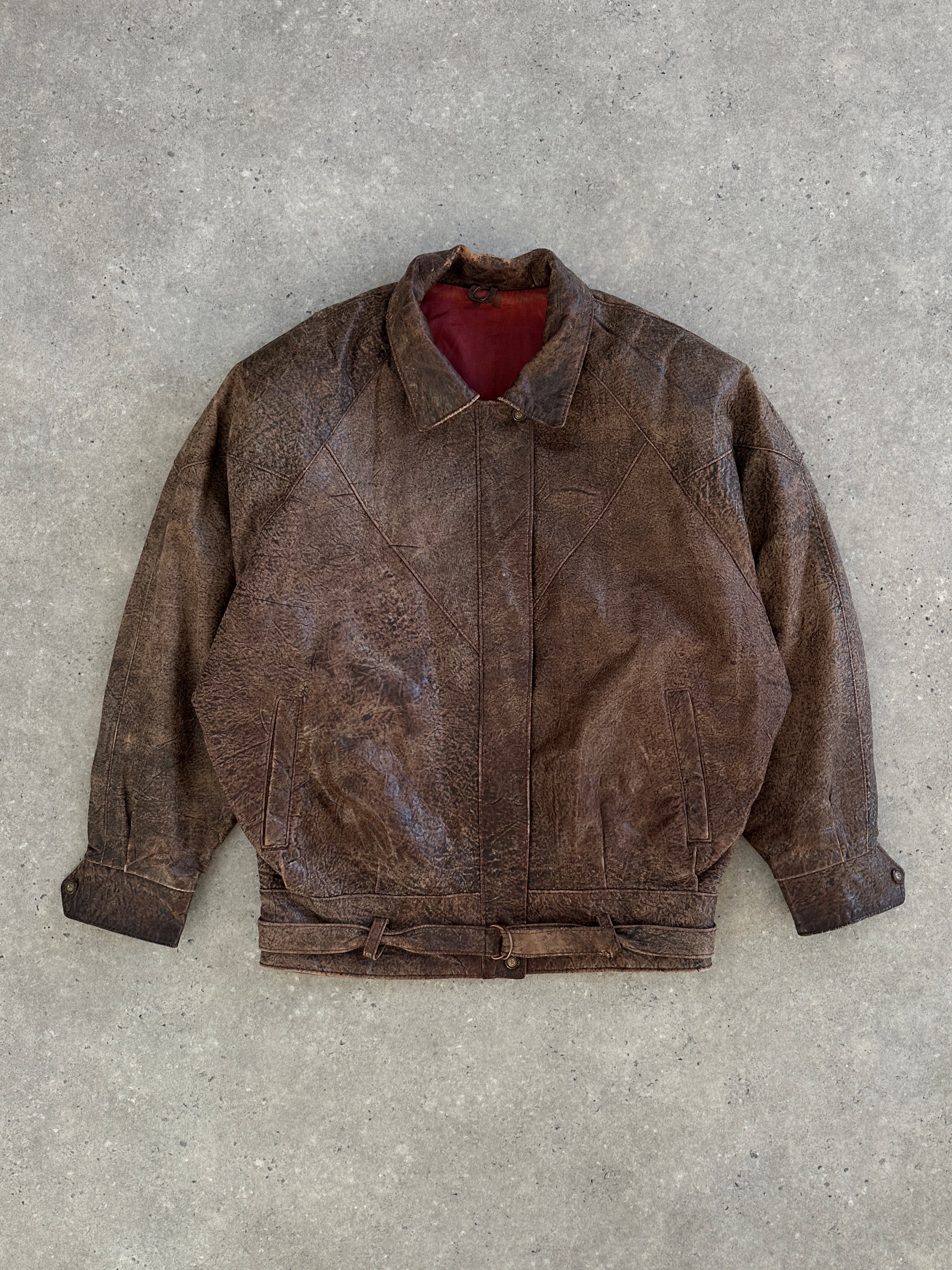 Vintage brand vintage 1980s aged leather jacket in size small, showing distressed brown leather with classic collar and front zipper.