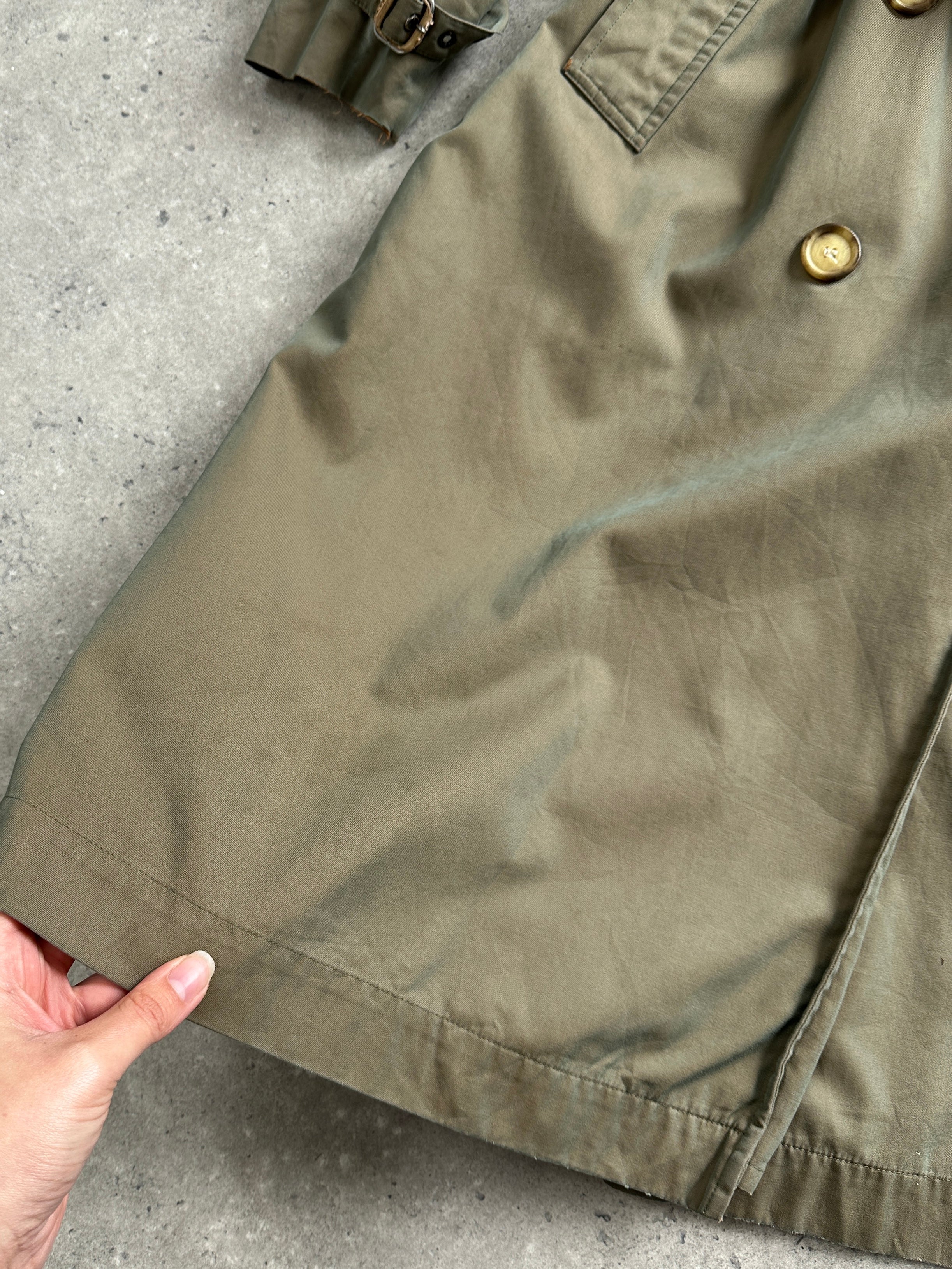Yves Saint Laurent Rive Gauche 1980s double-breasted trench coat in beige, labeled size L, hanging on a wooden hanger.