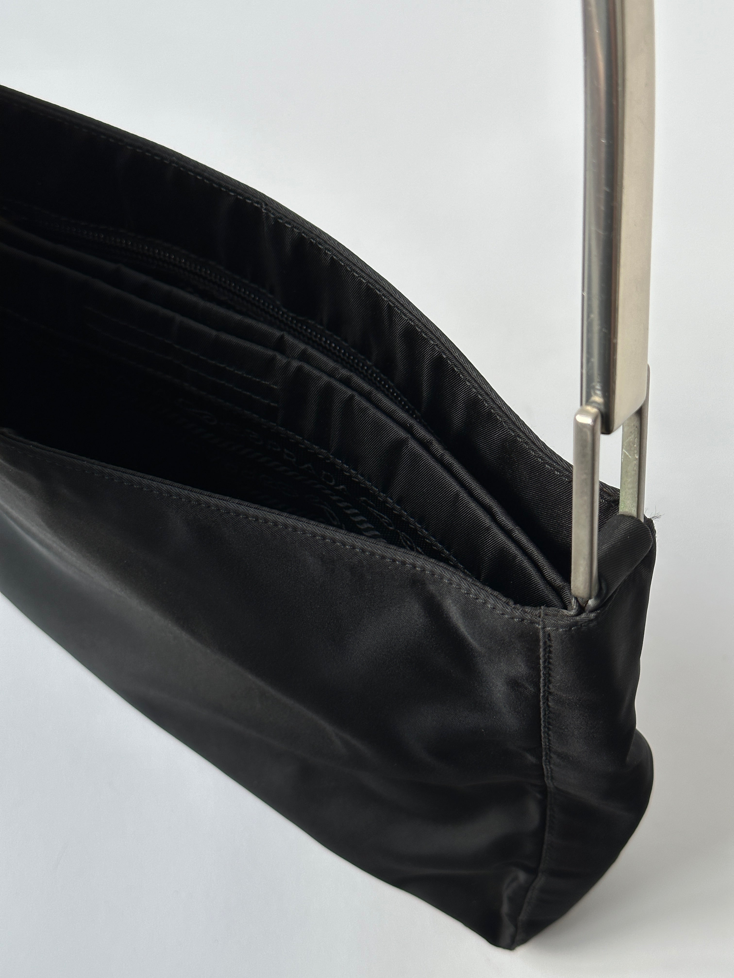 Prada nylon shoulder bag with metal handle and adjustable strap, featuring sleek design and modern style.