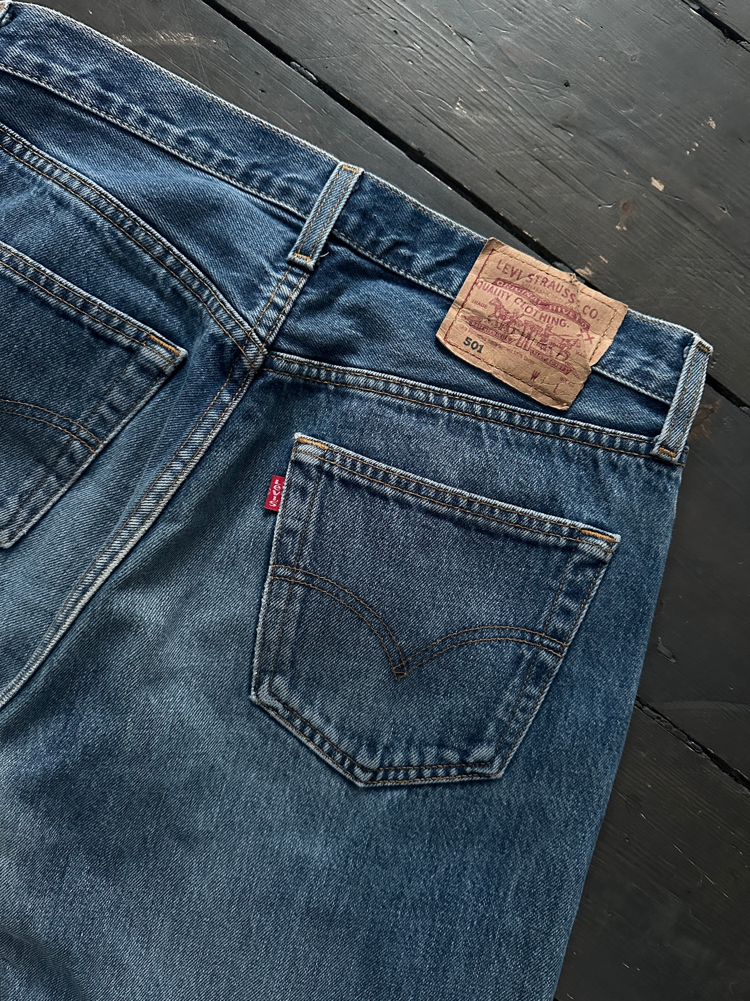 Levi’s 501 mid wash distressed straight leg denim jeans with W30 waist, shown on a hanger with a casual fit.