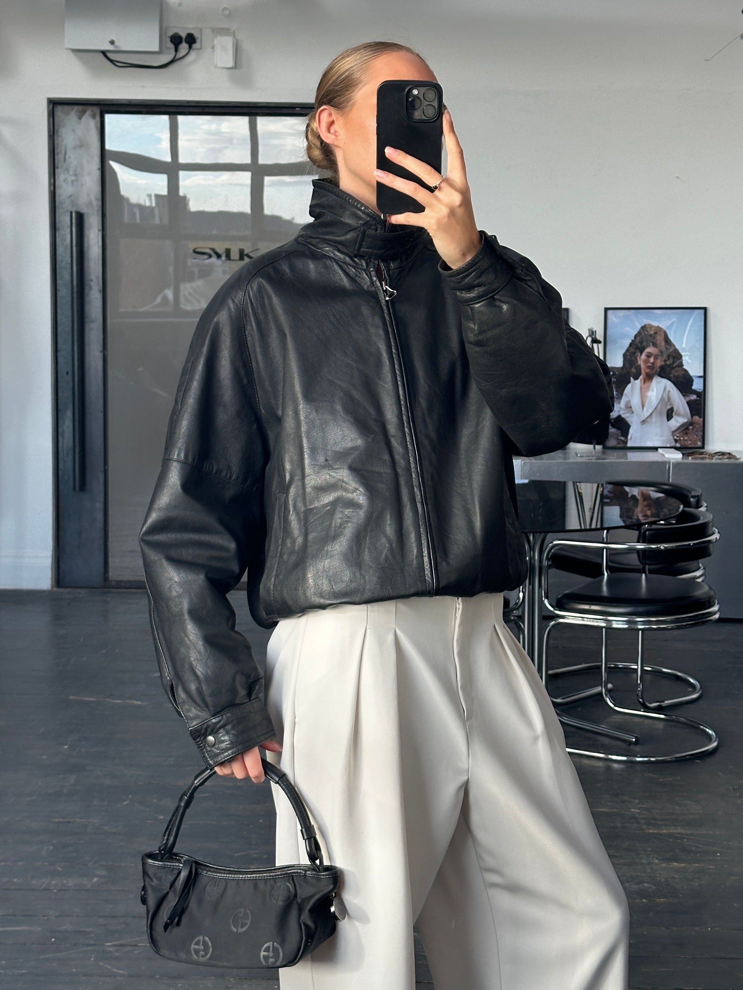 Vintage 1980s high neck leather bomber jacket in size large, featuring classic black leather with front zipper and ribbed cuffs.