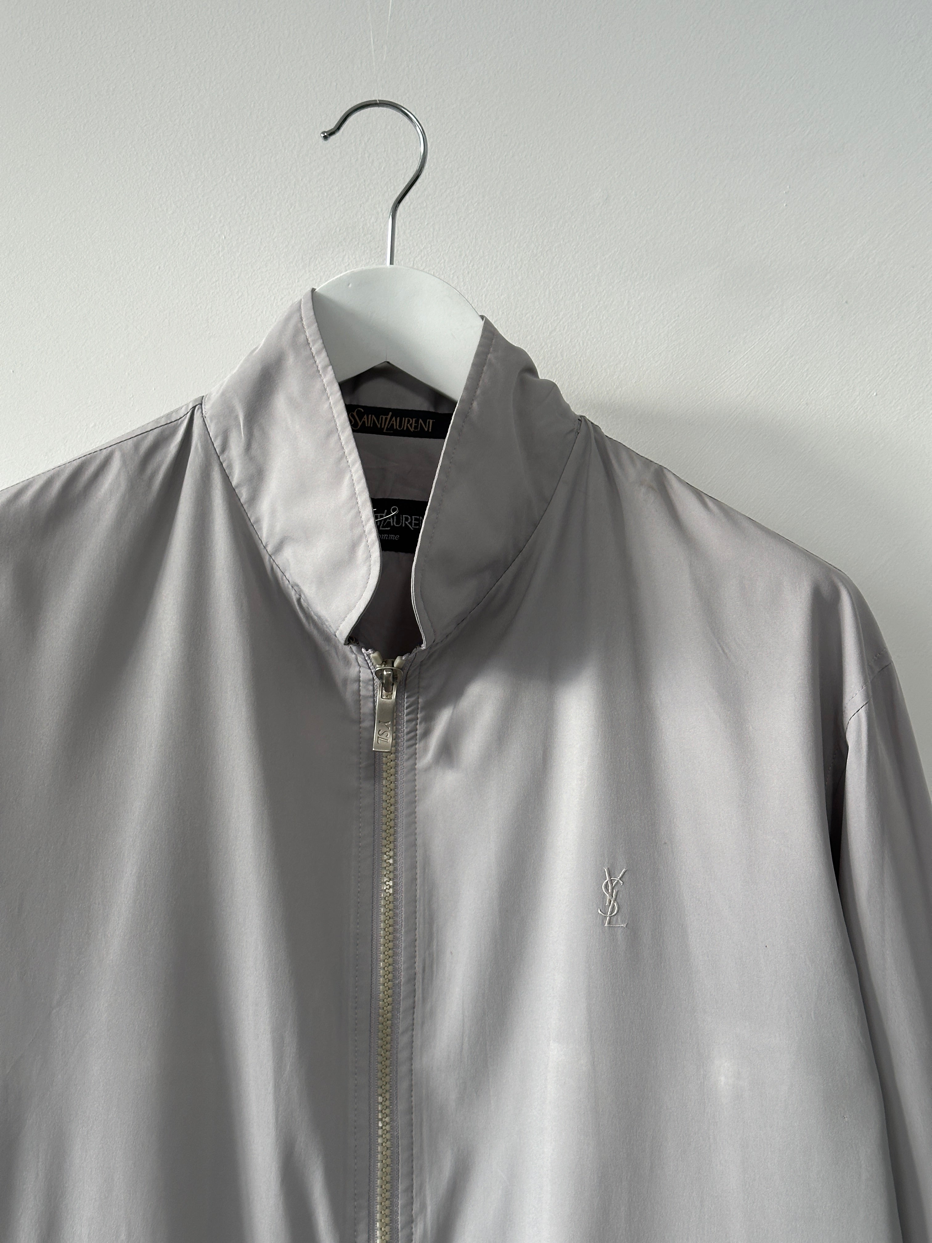 Yves Saint Laurent logo bomber jacket in size M, black with signature branding, displayed hanging on a plain background.