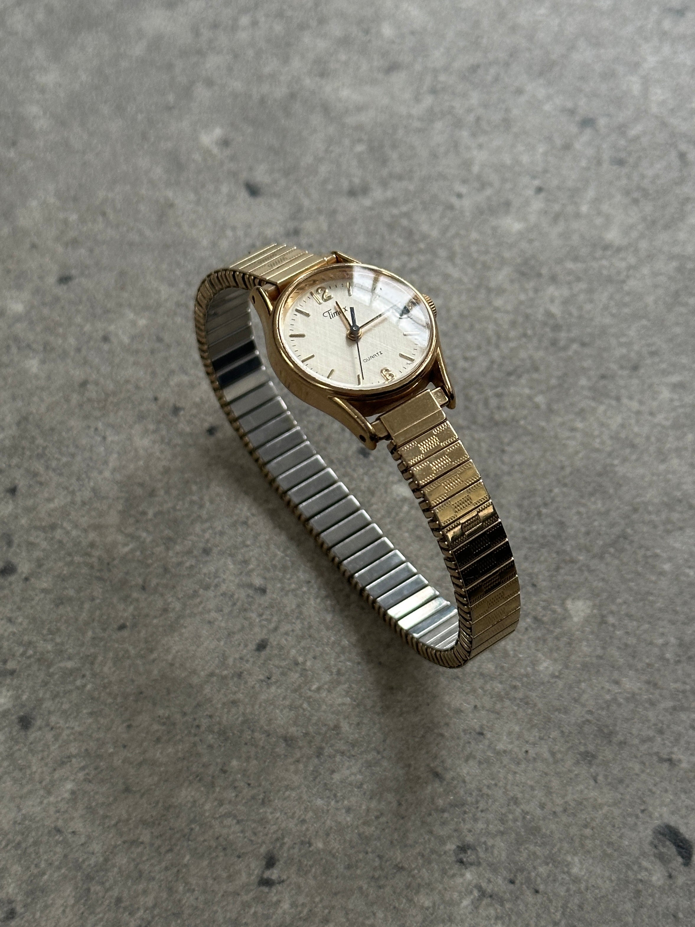 Timex 1990s round gold-tone quartz watch with classic design and metal bracelet, showcasing vintage style and timeless elegance.