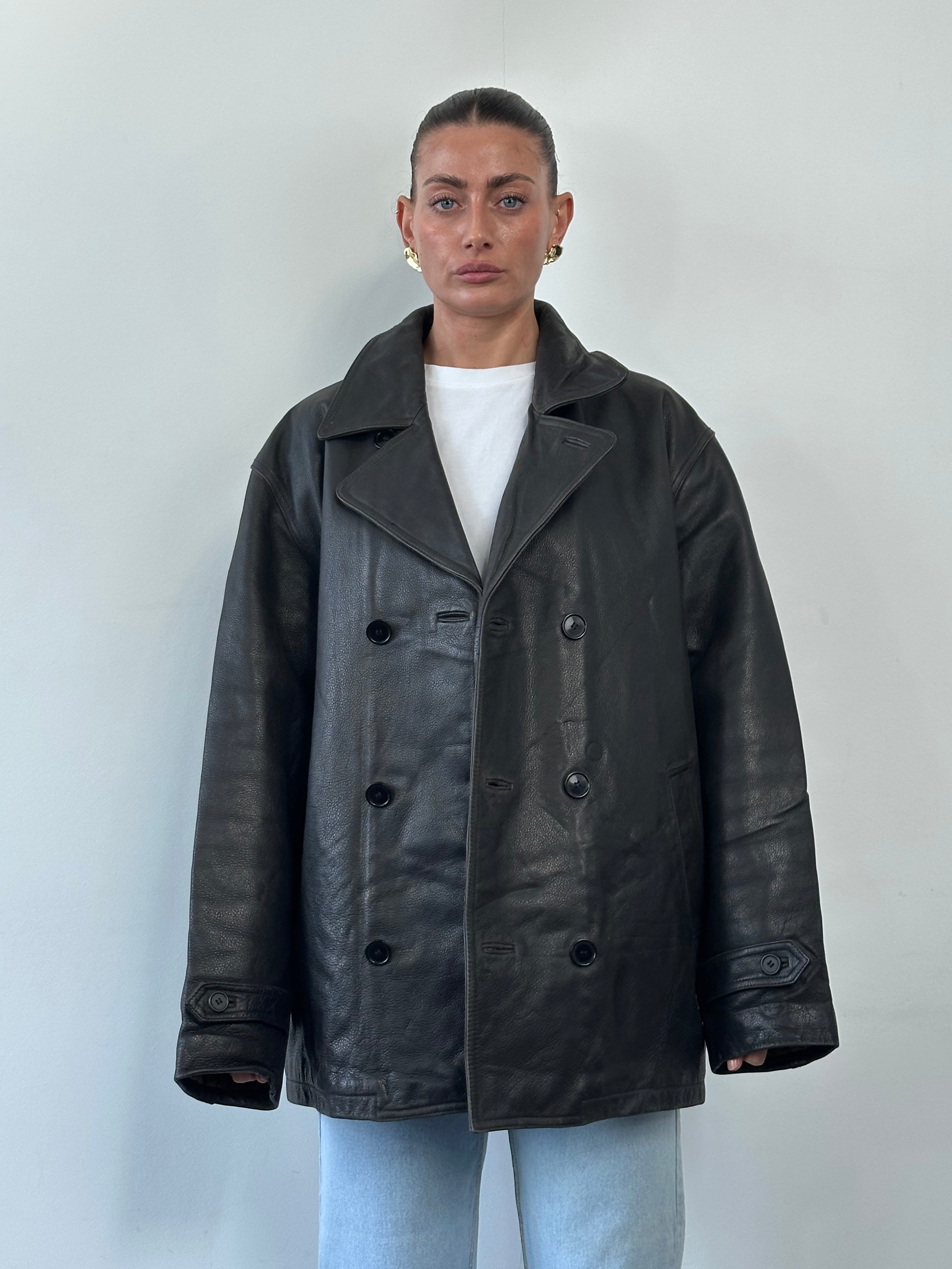 Tommy Hilfiger double-breasted leather jacket in XL, black with silver buttons, shown hanging on a wooden hanger.