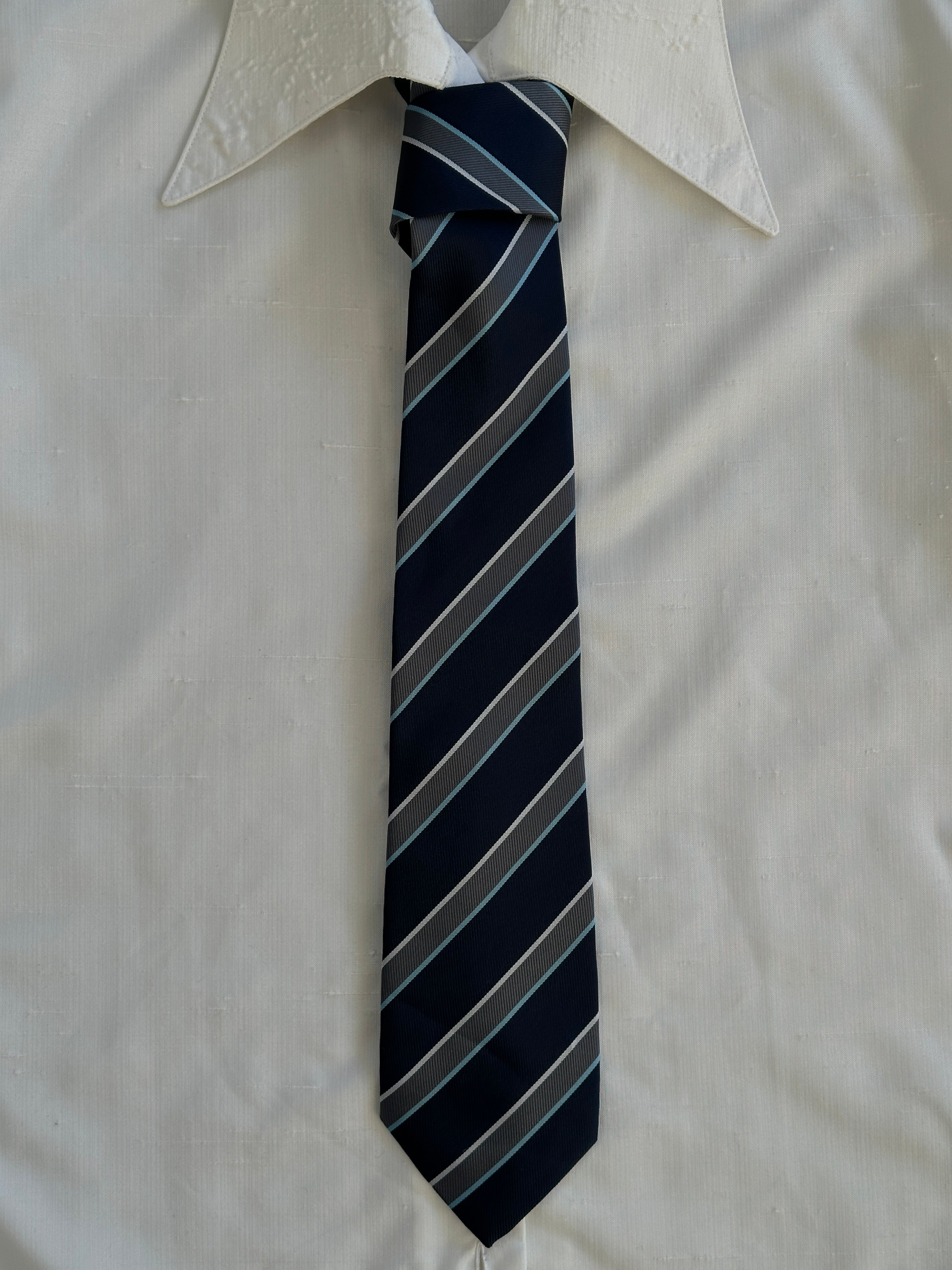 Vintage 1990s diagonal striped tie, classic men's accessory in navy, red, and cream colors, featuring a pointed tip and textured fabric.
