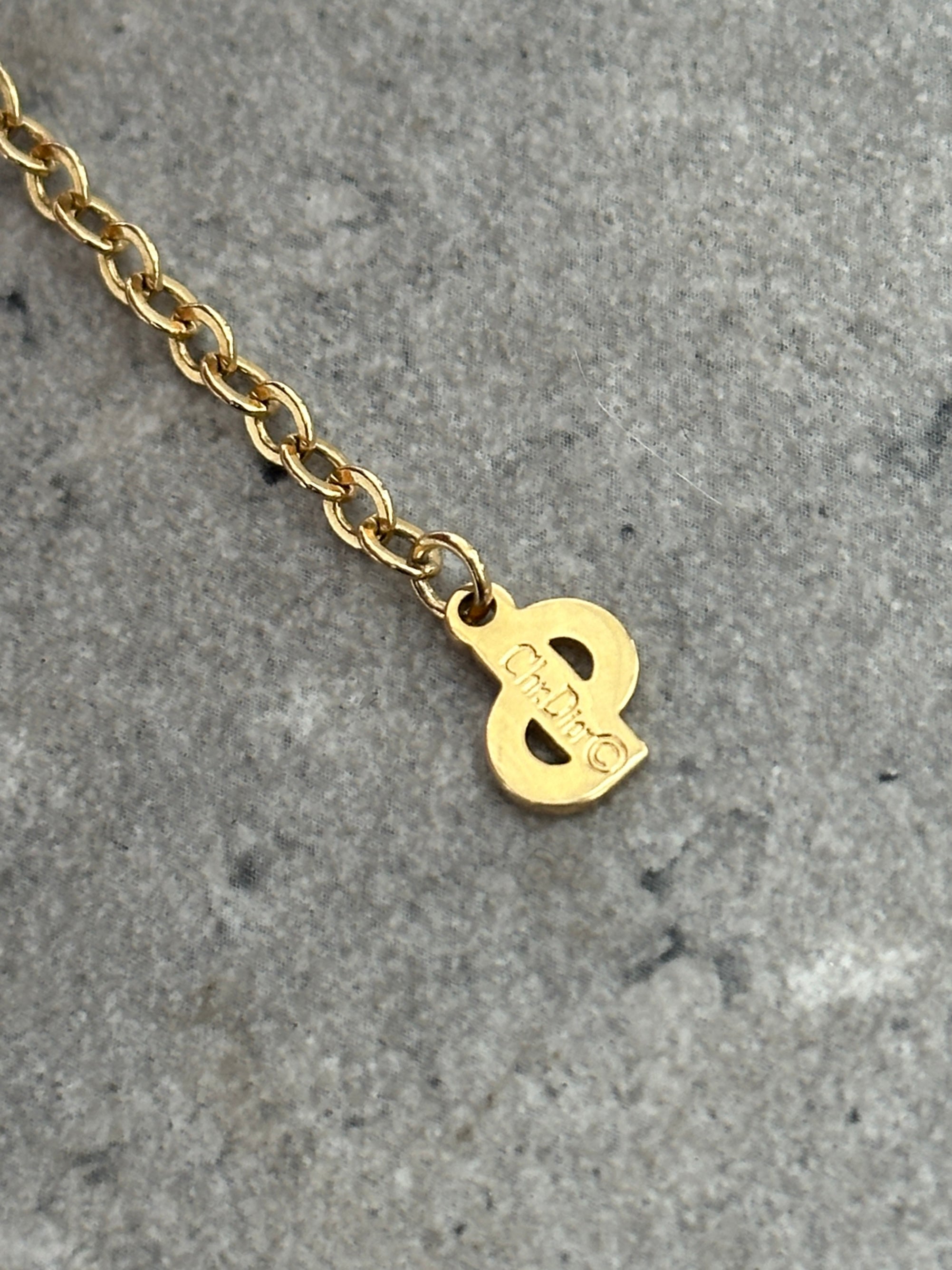 Christian Dior 18-inch gold-plated logo pendant necklace hanging on a chain, showcasing elegant jewelry design.