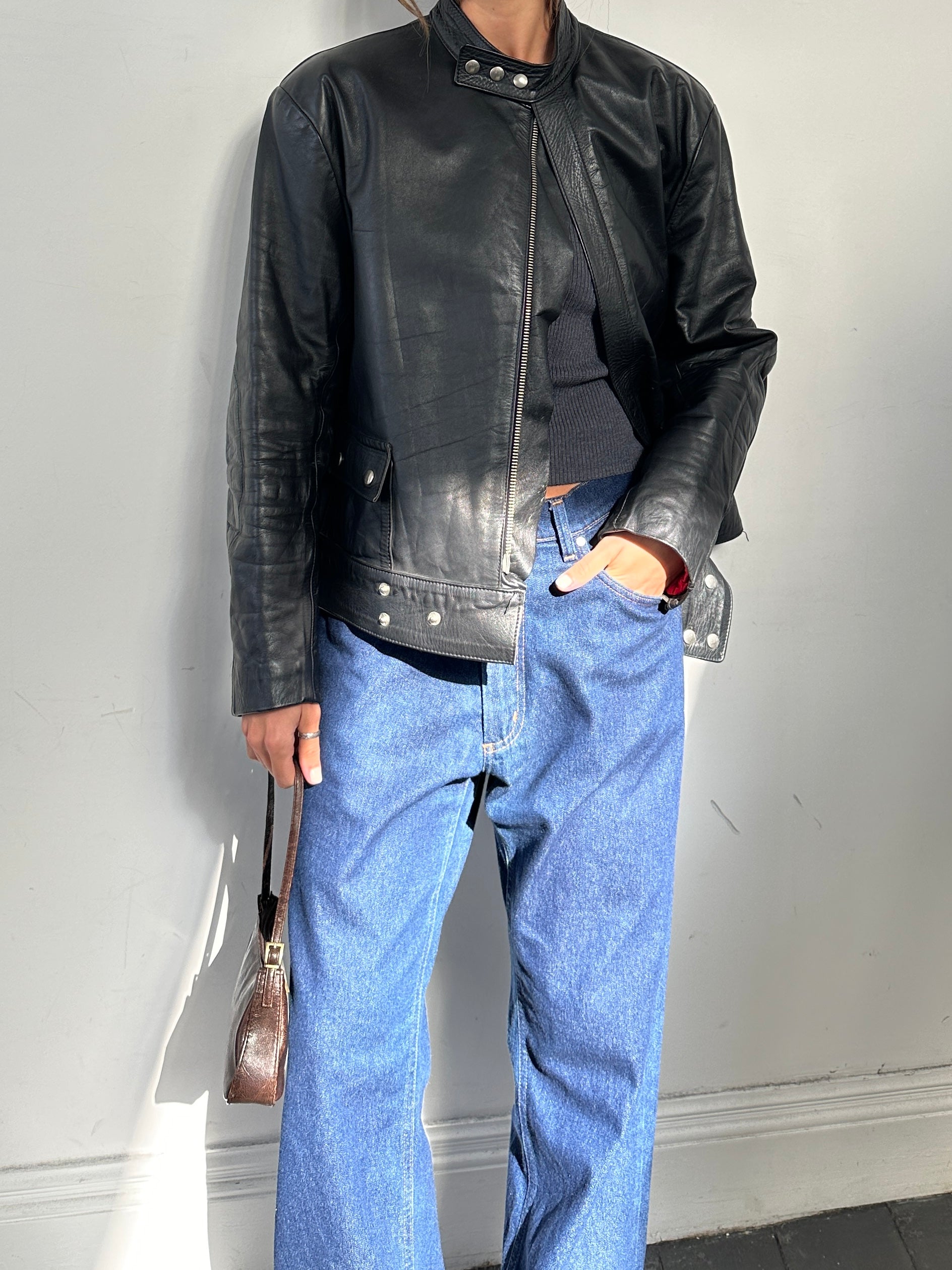 Vintage leather moto jacket in size large, featuring classic design and detailed stitching, displayed on a hanger.