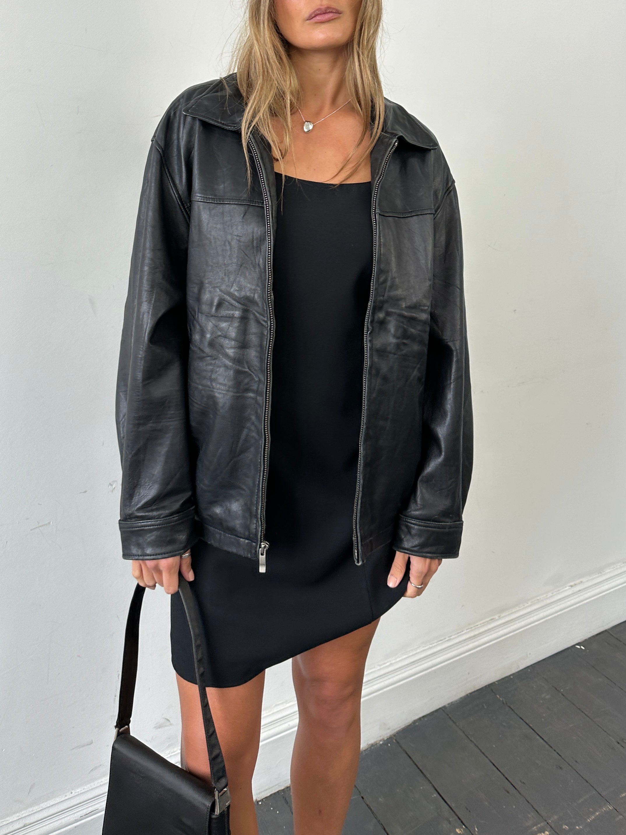 Vintage minimal leather jacket in size L/XL, featuring a sleek design and classic style, shown on a hanger.