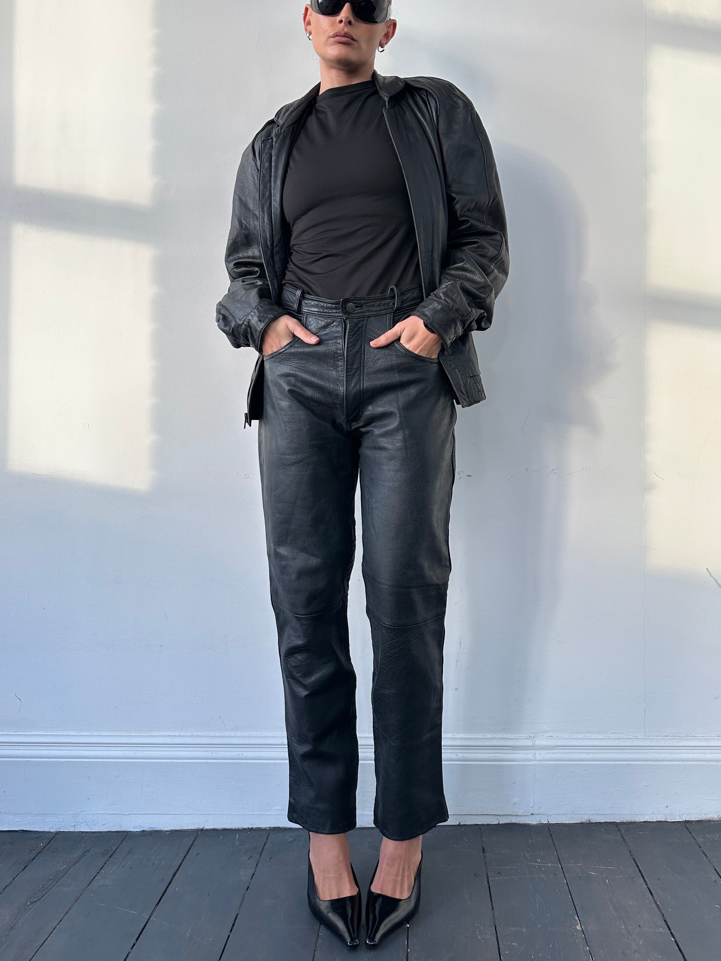 Vintage high waisted straight leg leather trousers, size W28, shown on model with classic vintage style.