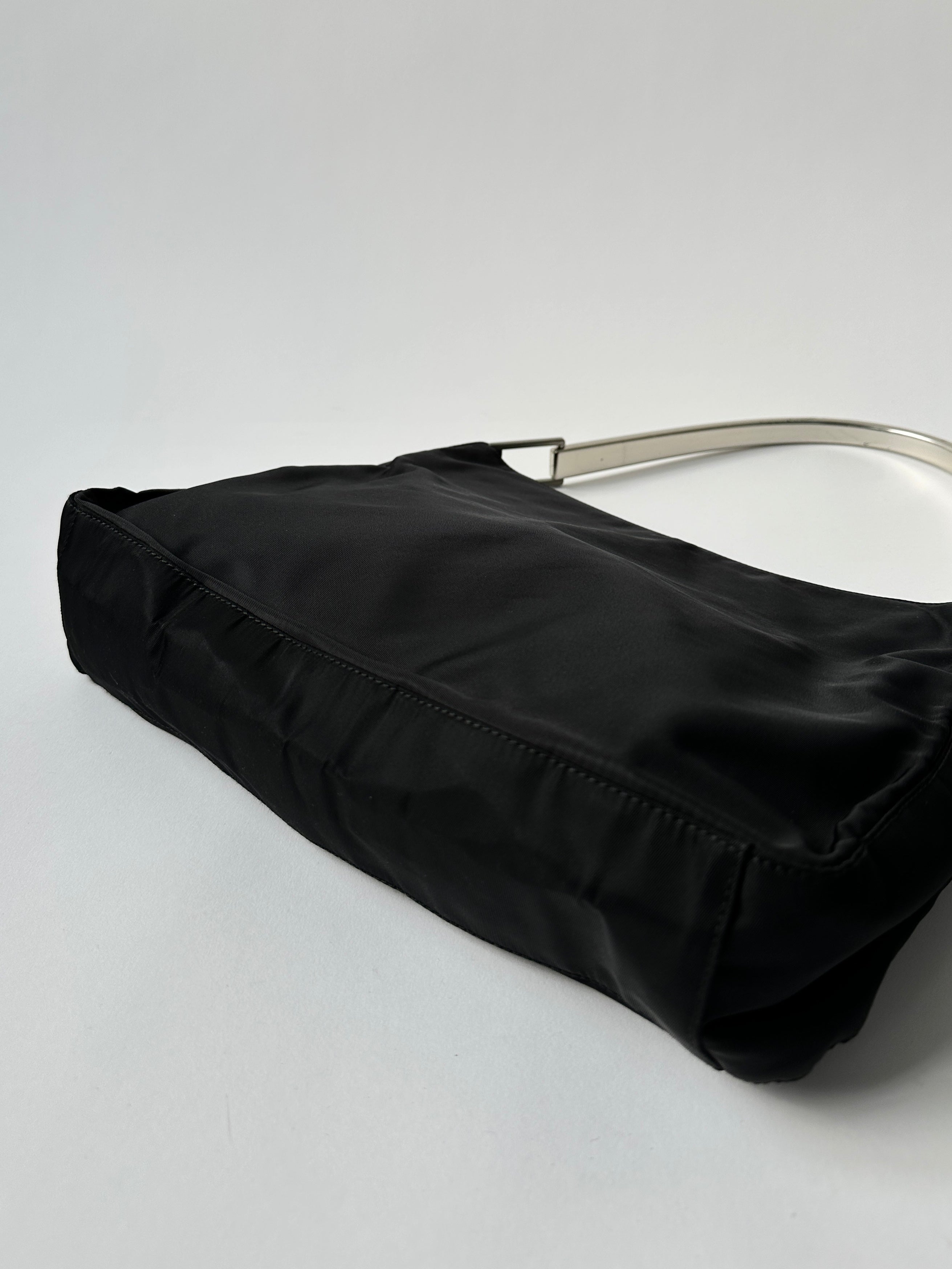 Prada nylon shoulder bag with metal handle, showcasing sleek design and durable nylon material.