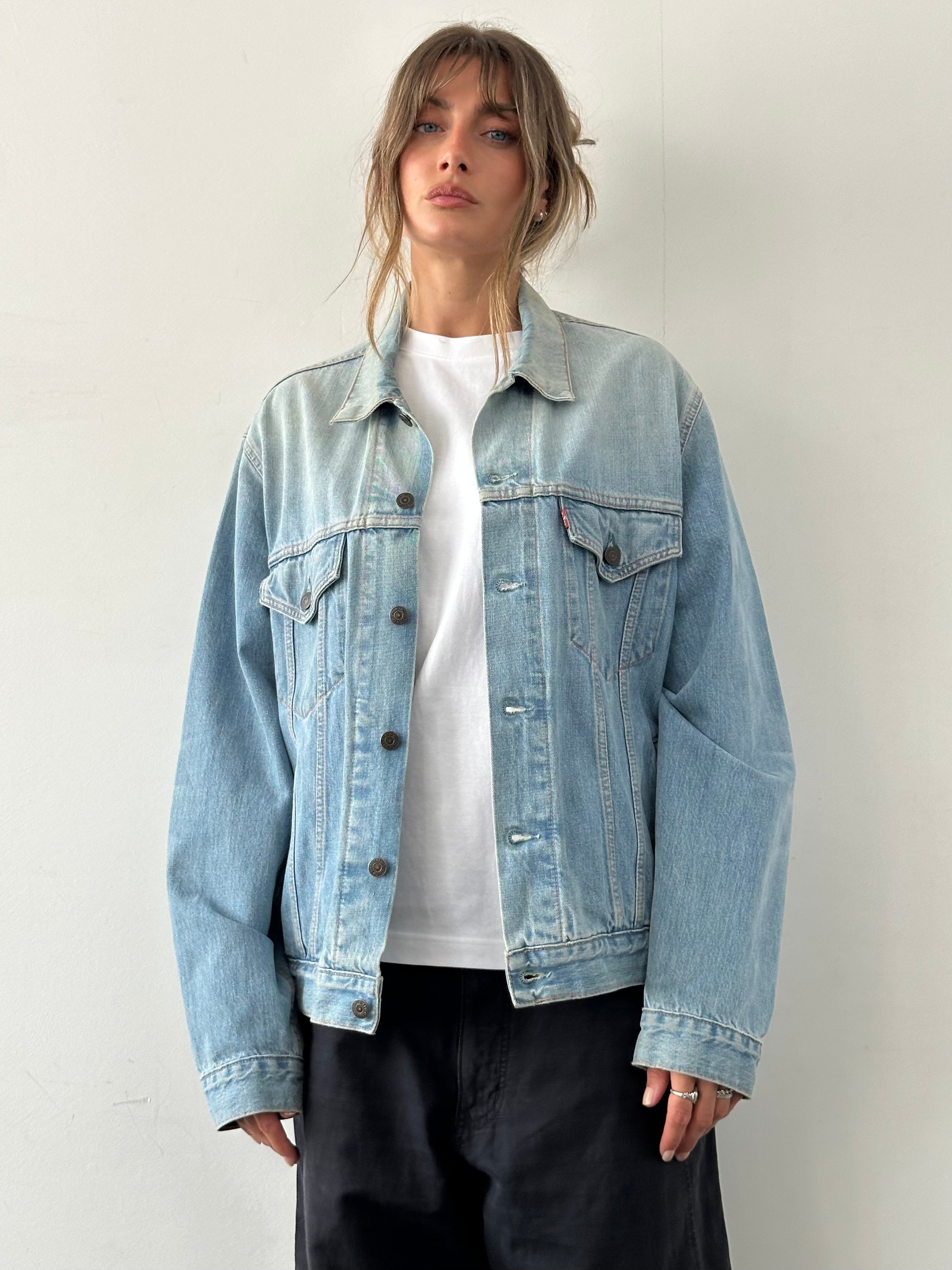 Levi’s faded denim jacket in size L displayed on a hanger, showcasing classic style and distressed denim fabric.