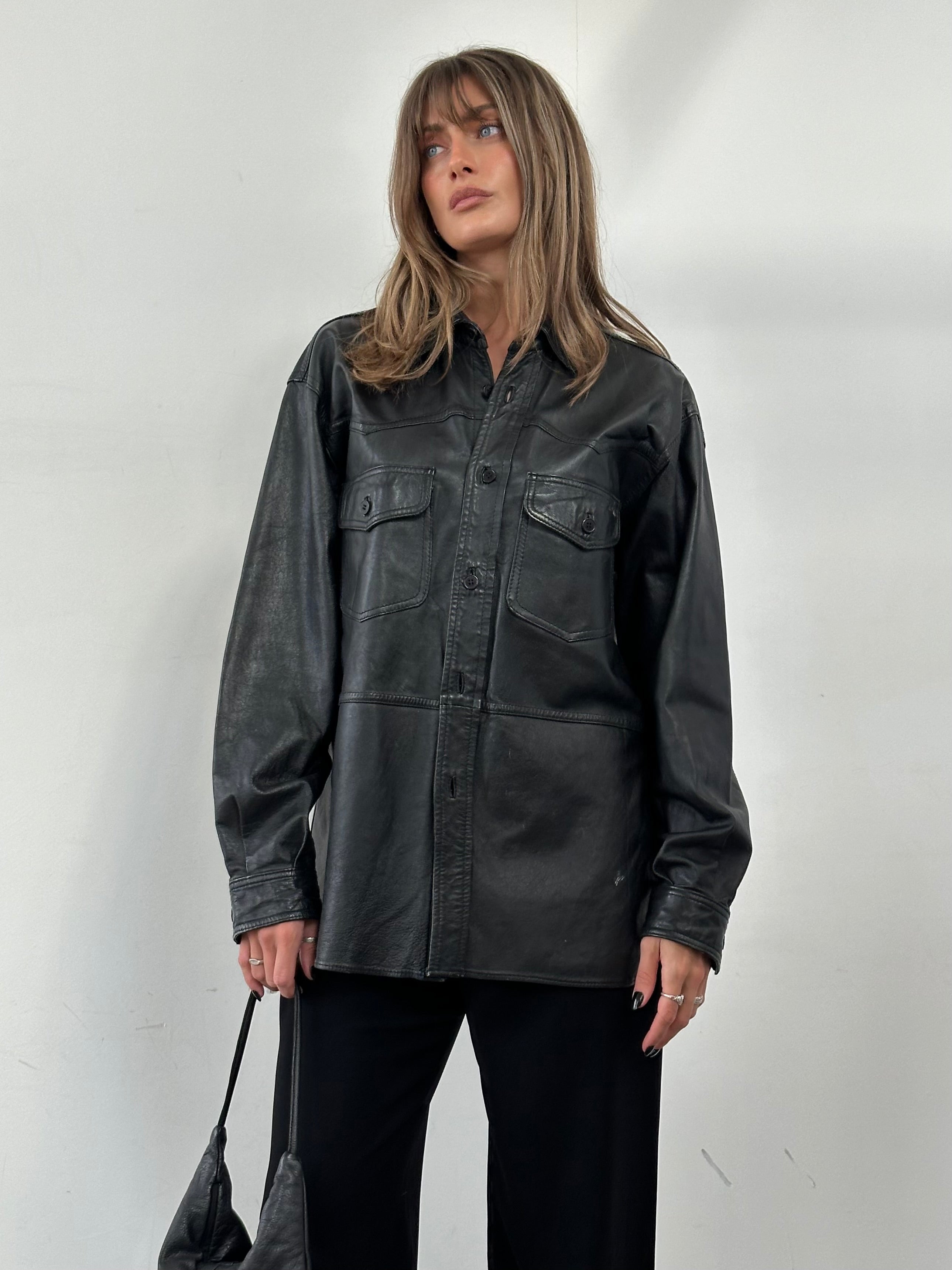 Vintage leather shirt in size L/XL, featuring classic design and durable leather material, displayed on a hanger.