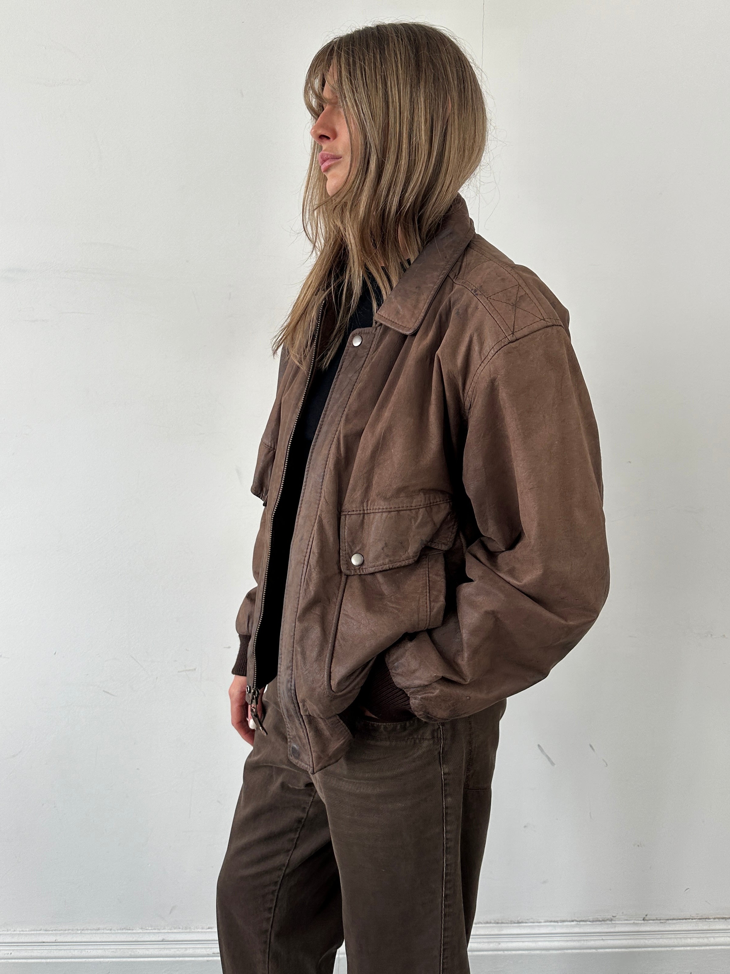 Vintage leather bomber jacket in size large, featuring classic design and detailed stitching, displayed on a hanger.