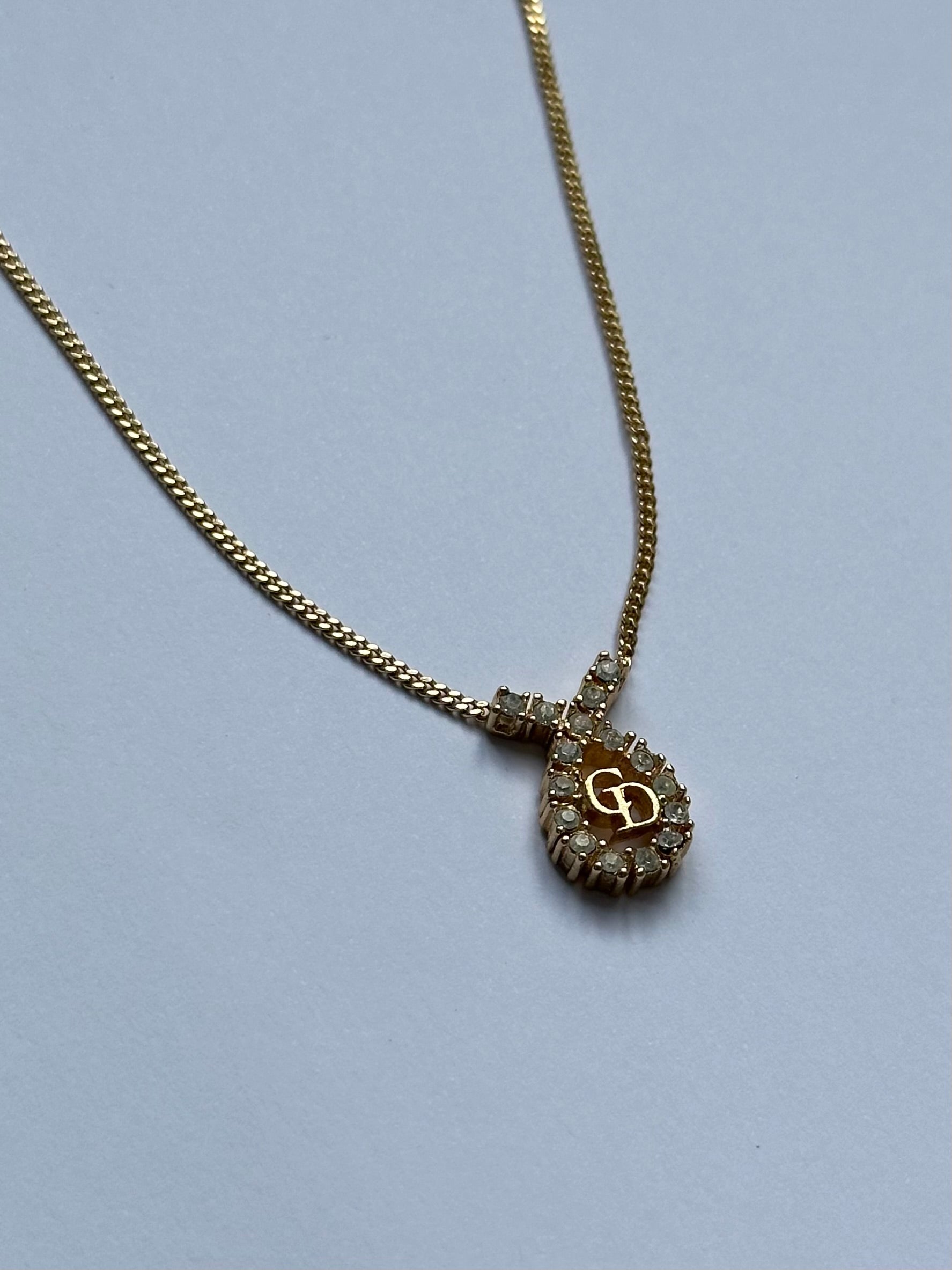 Christian Dior 16-inch gold plated rhinestone drop logo pendant necklace, showcasing elegant jewelry design.