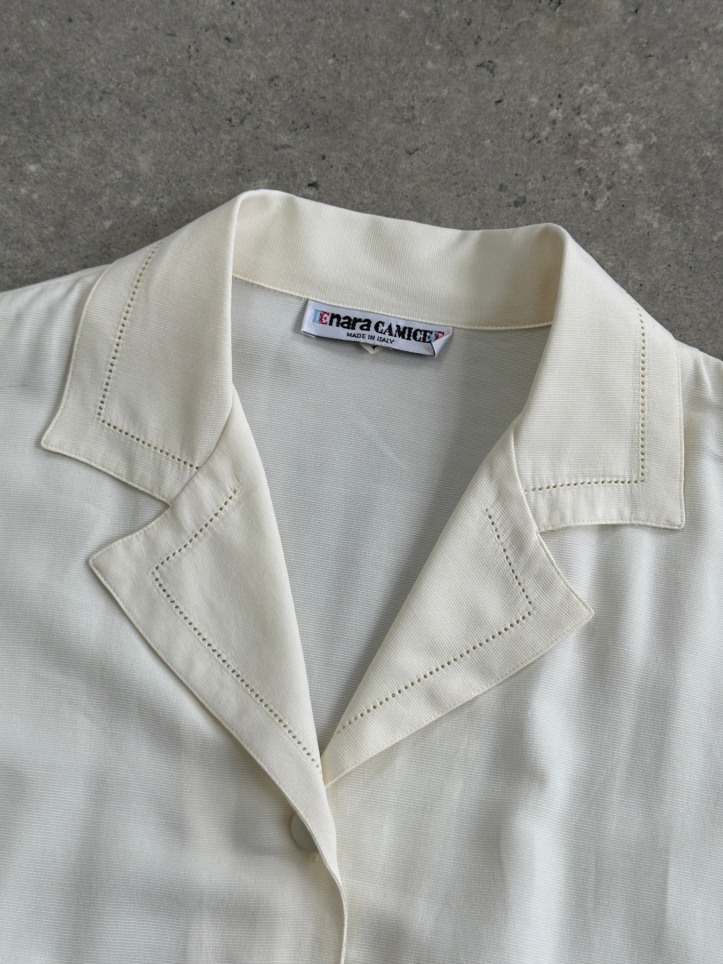 Vintage Italian vintage fitted blouse with open collar, short sleeves, and tailored design, displayed on a hanger.