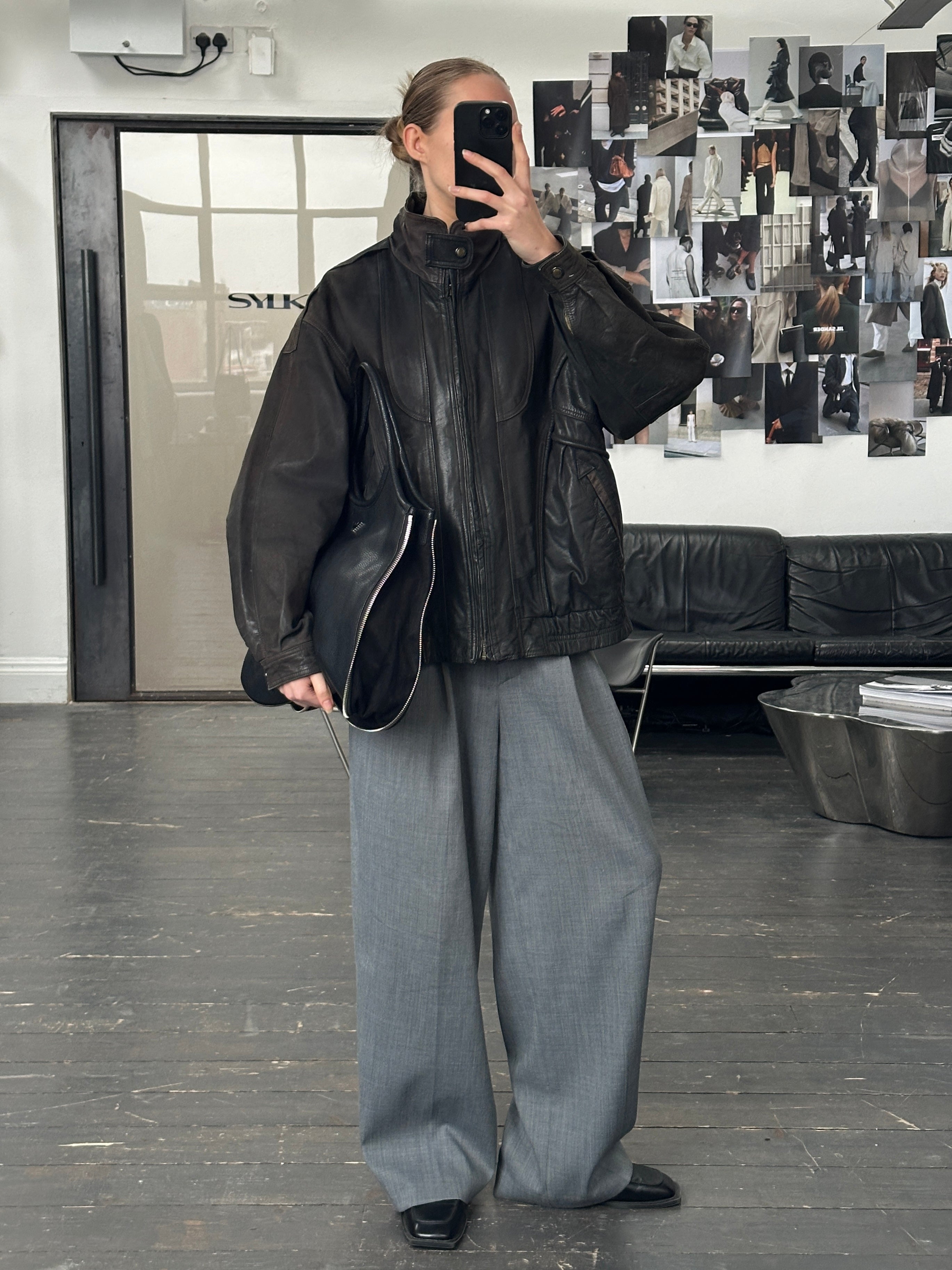 Vintage 1990s aged leather bomber jacket in XL, featuring distressed leather and classic style, displayed on a hanger.