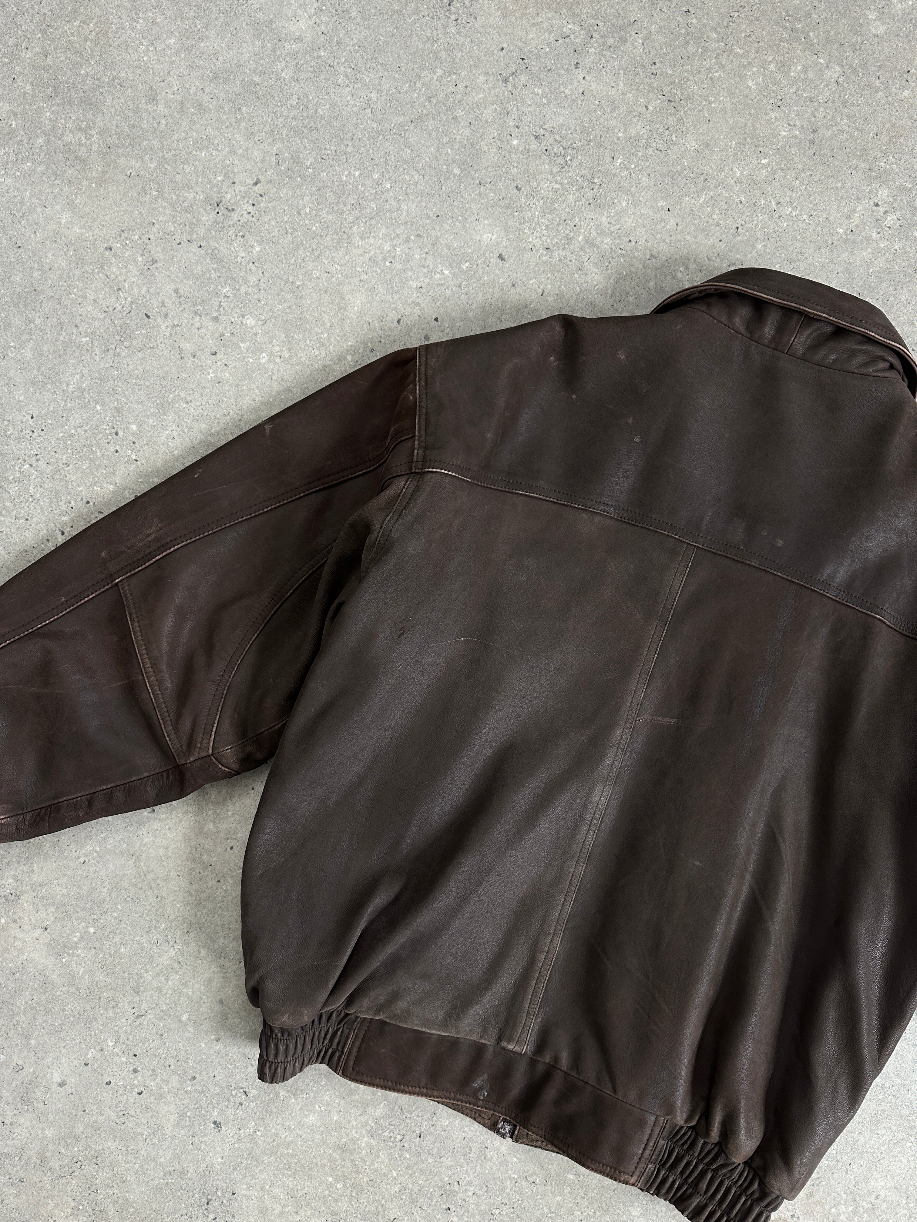 Vintage distressed leather bomber jacket for men, showing a rugged, worn-in style with a classic fit and detailed stitching.