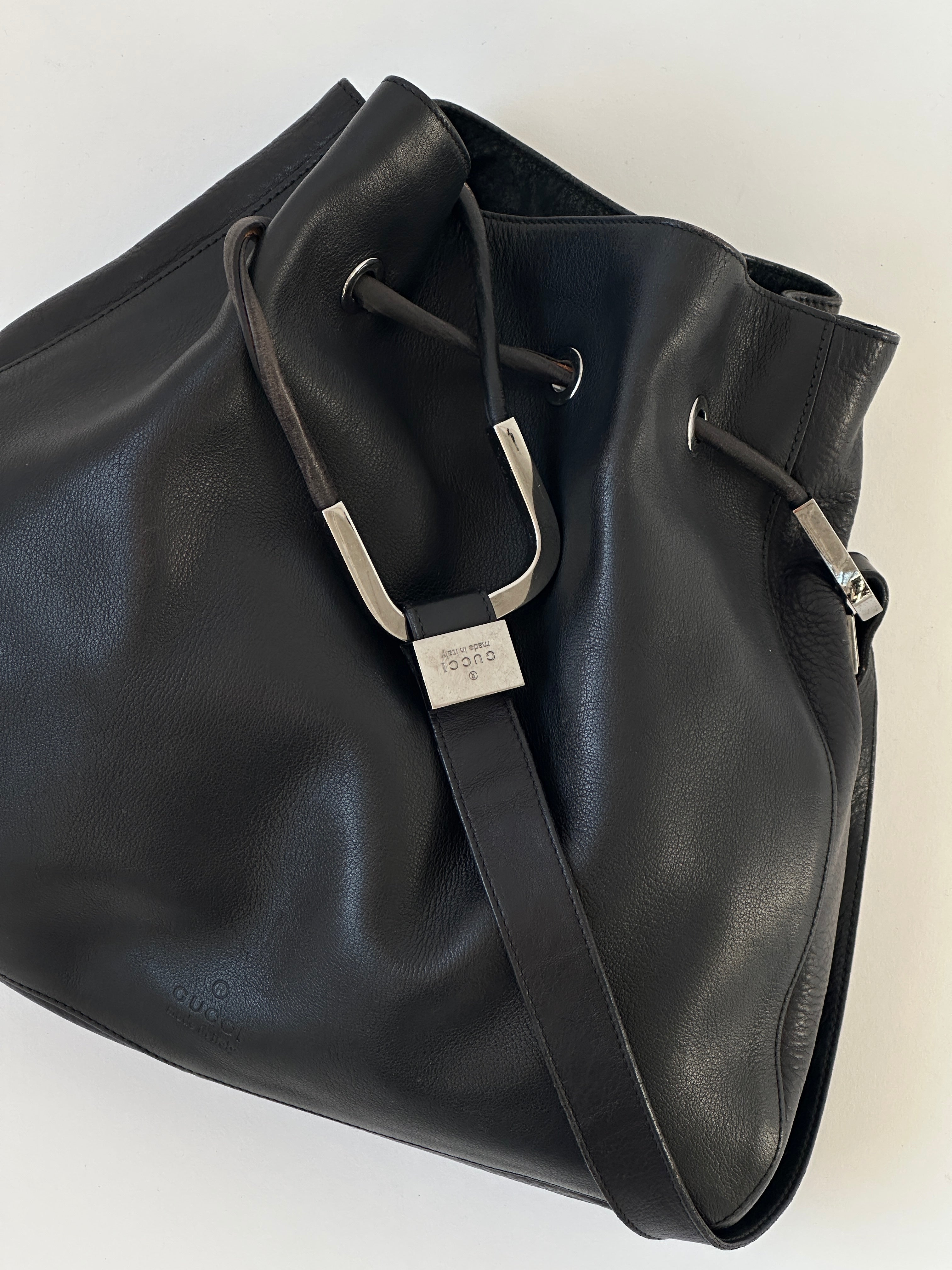 Gucci leather bucket bag with adjustable strap, featuring signature GG monogram pattern and gold-tone hardware.