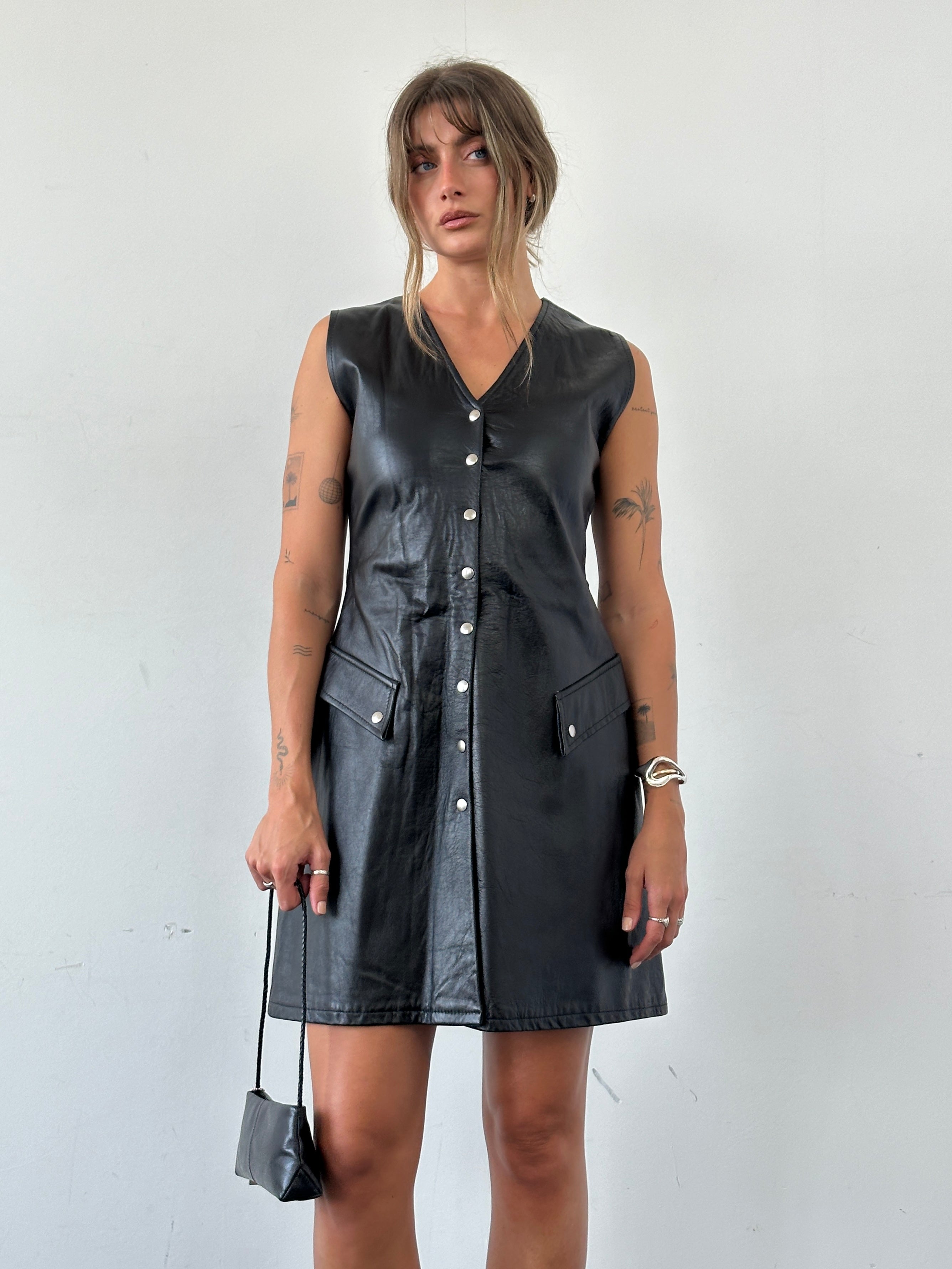 Vintage fitted leather button-up dress, size small, featuring a classic collar and sleek silhouette, shown on a hanger.