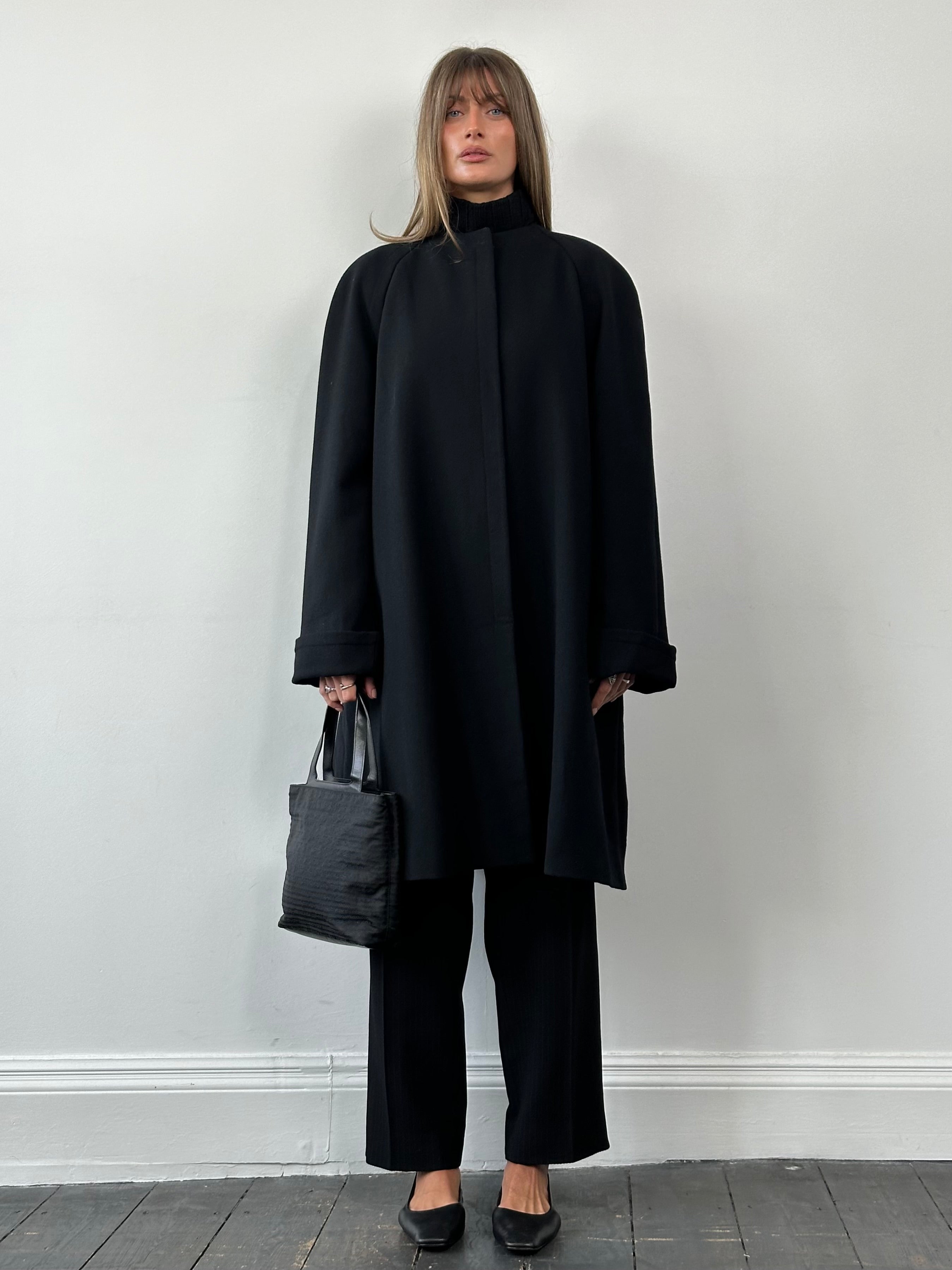 Gianfranco Ferre pure wool A-line collarless coat in XL, shown hanging on a wooden rack, with a minimalist design and clean lines.