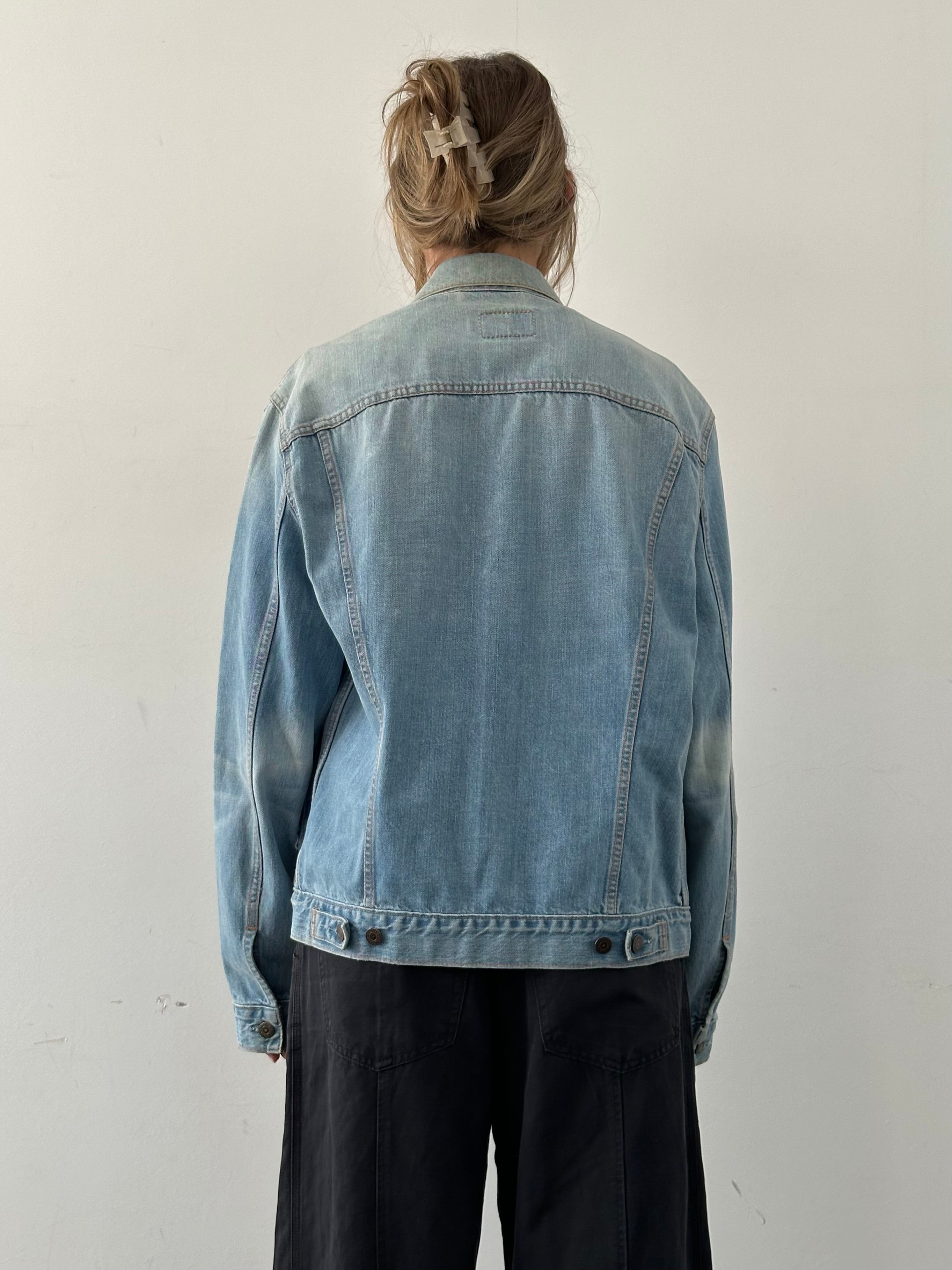 Levi’s faded denim jacket in size L displayed on a hanger, showcasing classic casual style and distressed fabric details.