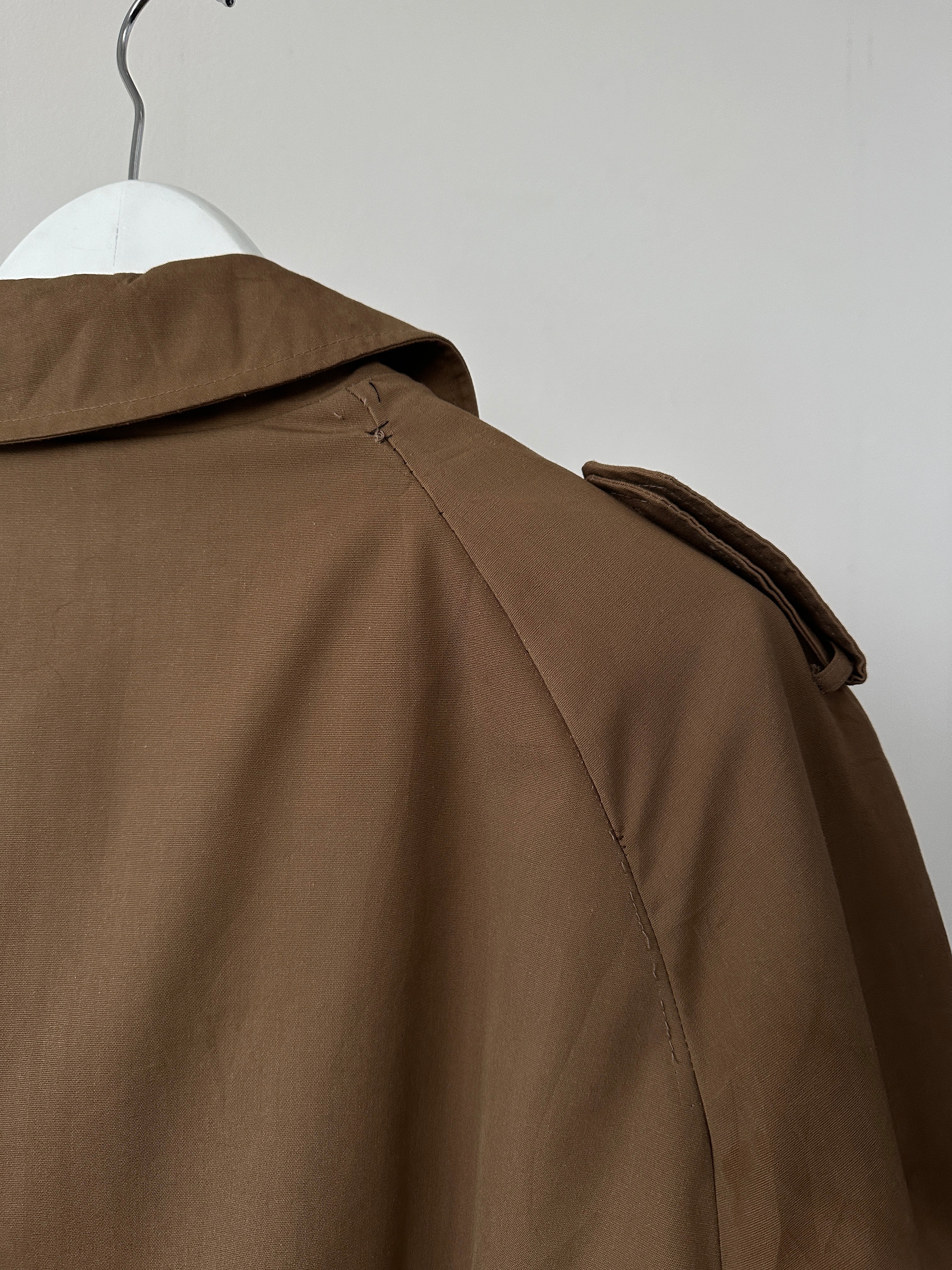 Christian Dior cotton double-breasted trench coat in size L displayed on a hanger with classic design and neutral color.