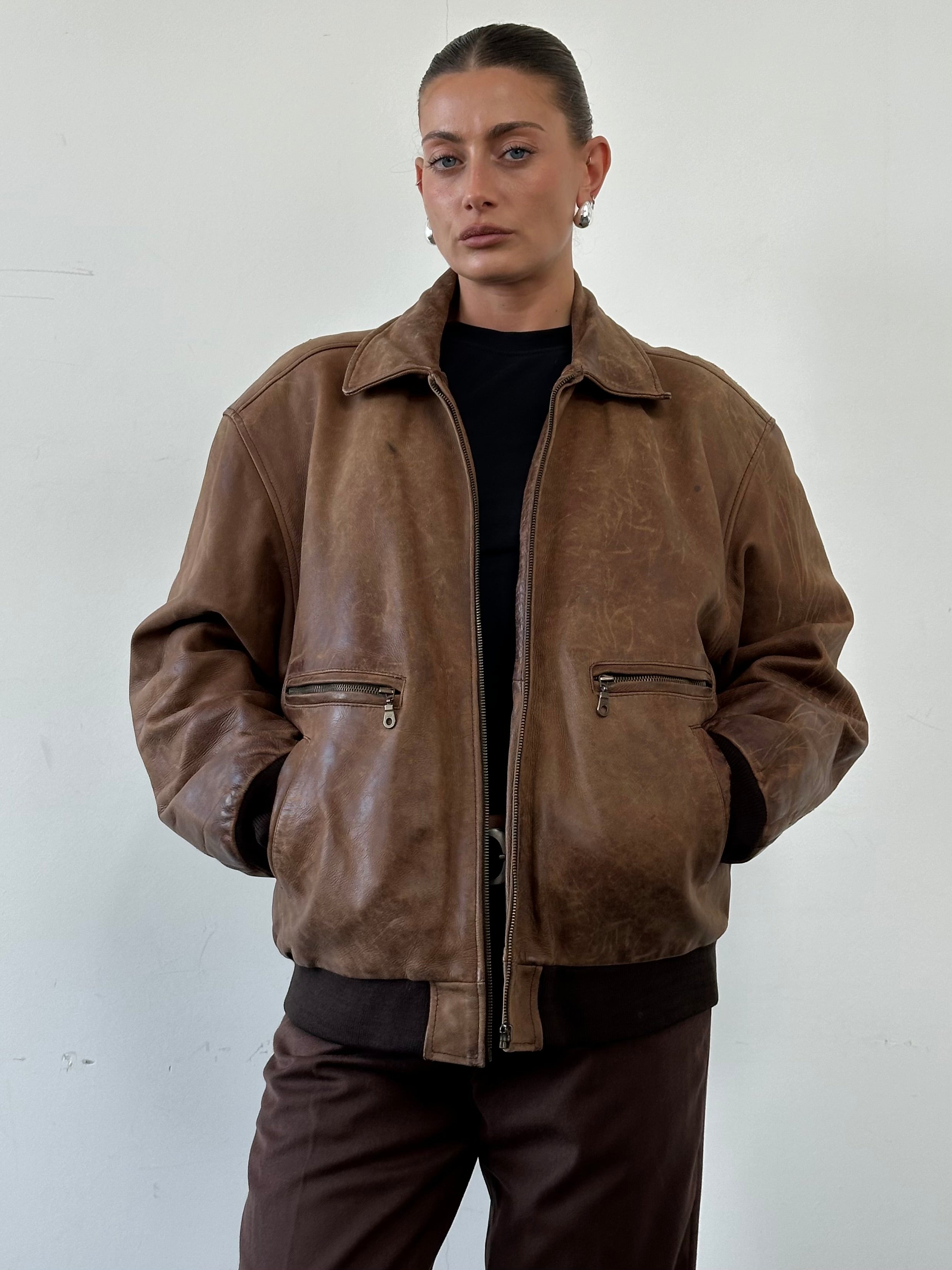 Vintage distressed leather bomber jacket in XL size, featuring rugged design and classic style, front view with collar and zipper.