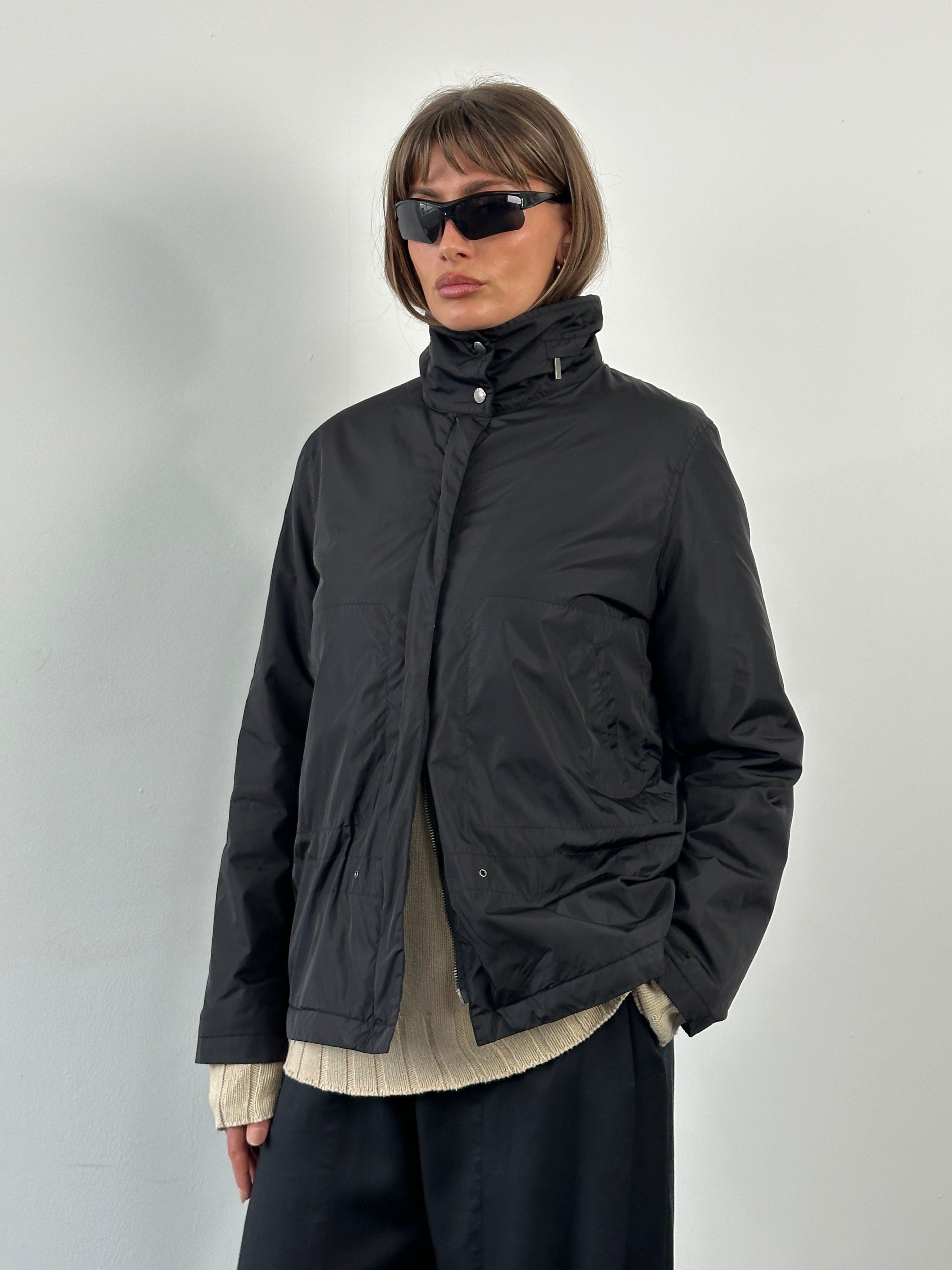 Burberry London 2000s nylon high neck jacket in black, featuring a high collar and zip closure, displayed on a hanger.