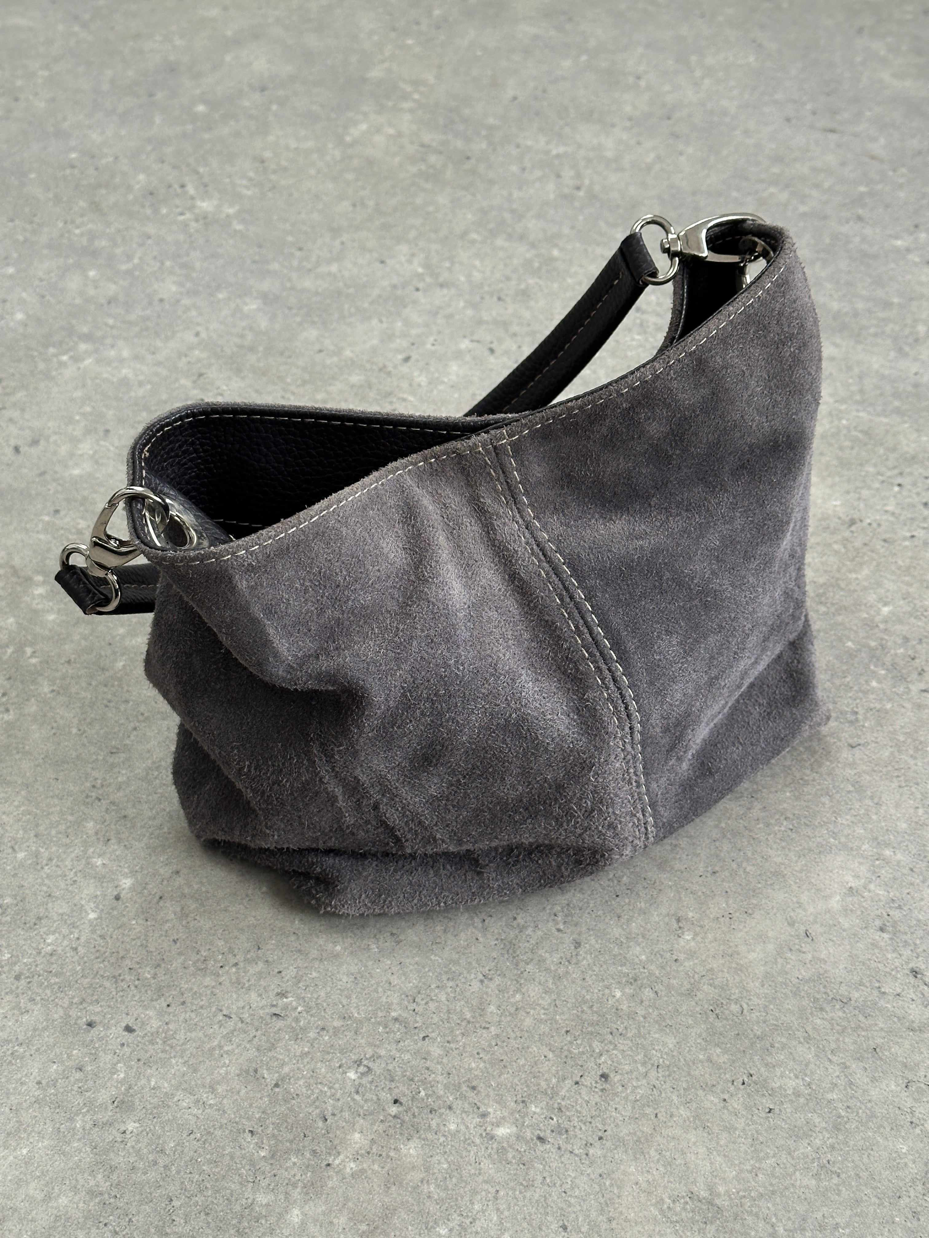 Vintage suede leather shoulder bag with adjustable strap and rustic finish, showcasing a stylish and timeless accessory.