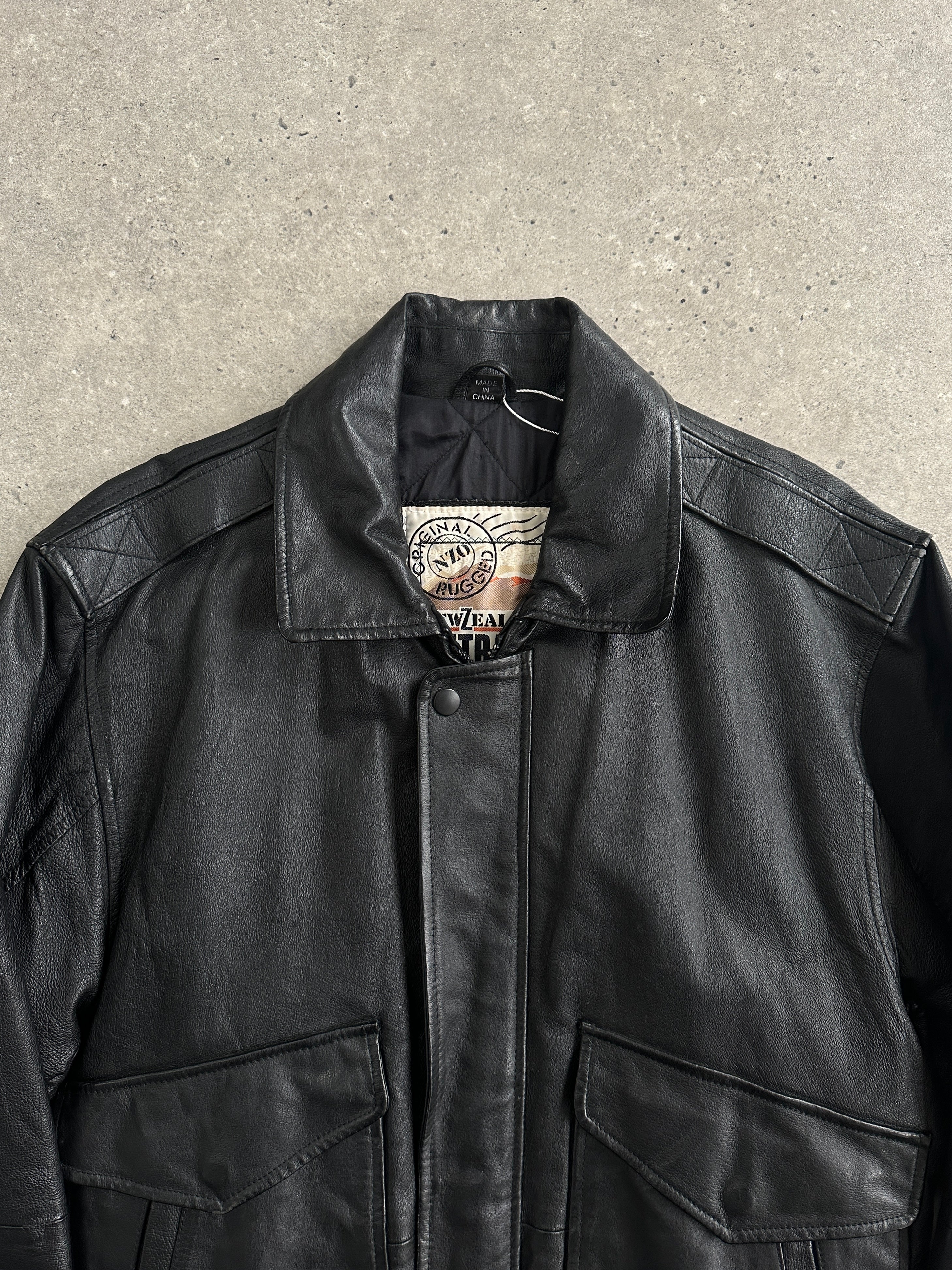 Vintage leather bomber jacket in size M/L, featuring classic design and durable construction, displayed on a hanger.