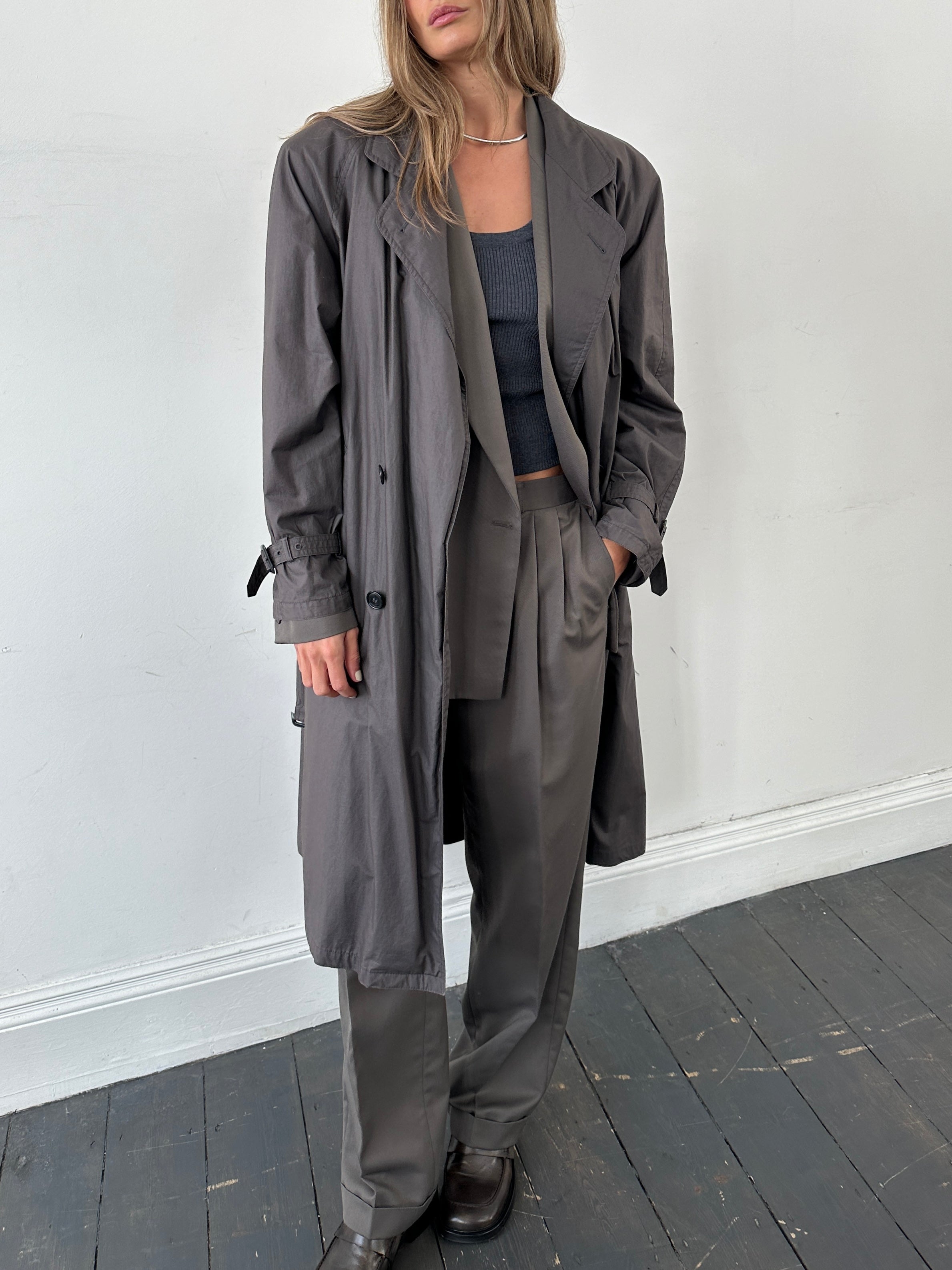 Vintage double-breasted unlined belted trench coat in size L, shown hanging with classic collar and tailored fit.