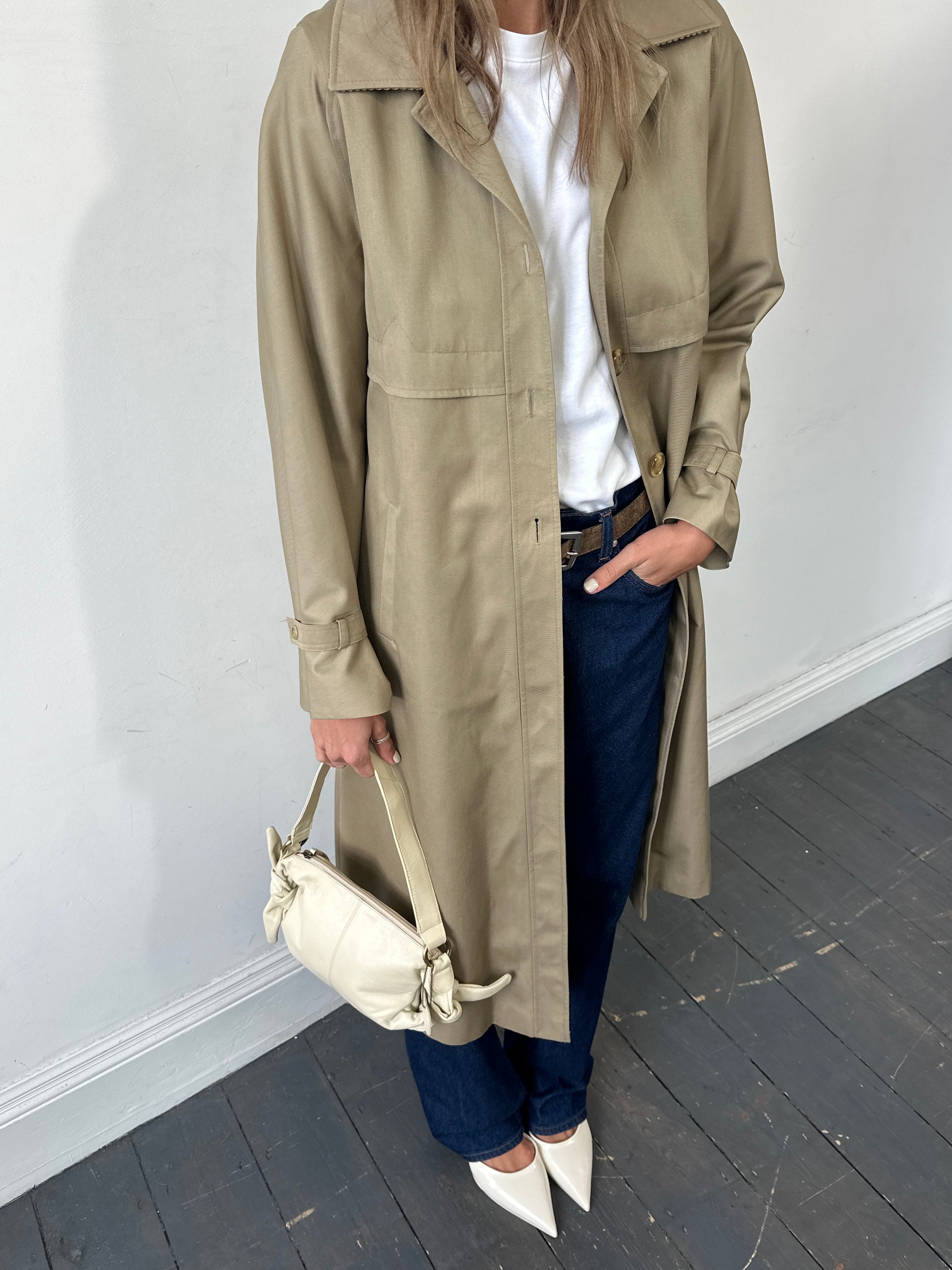 Vintage single-breasted trench coat in size small, displayed on a hanger, featuring classic design and durable fabric.