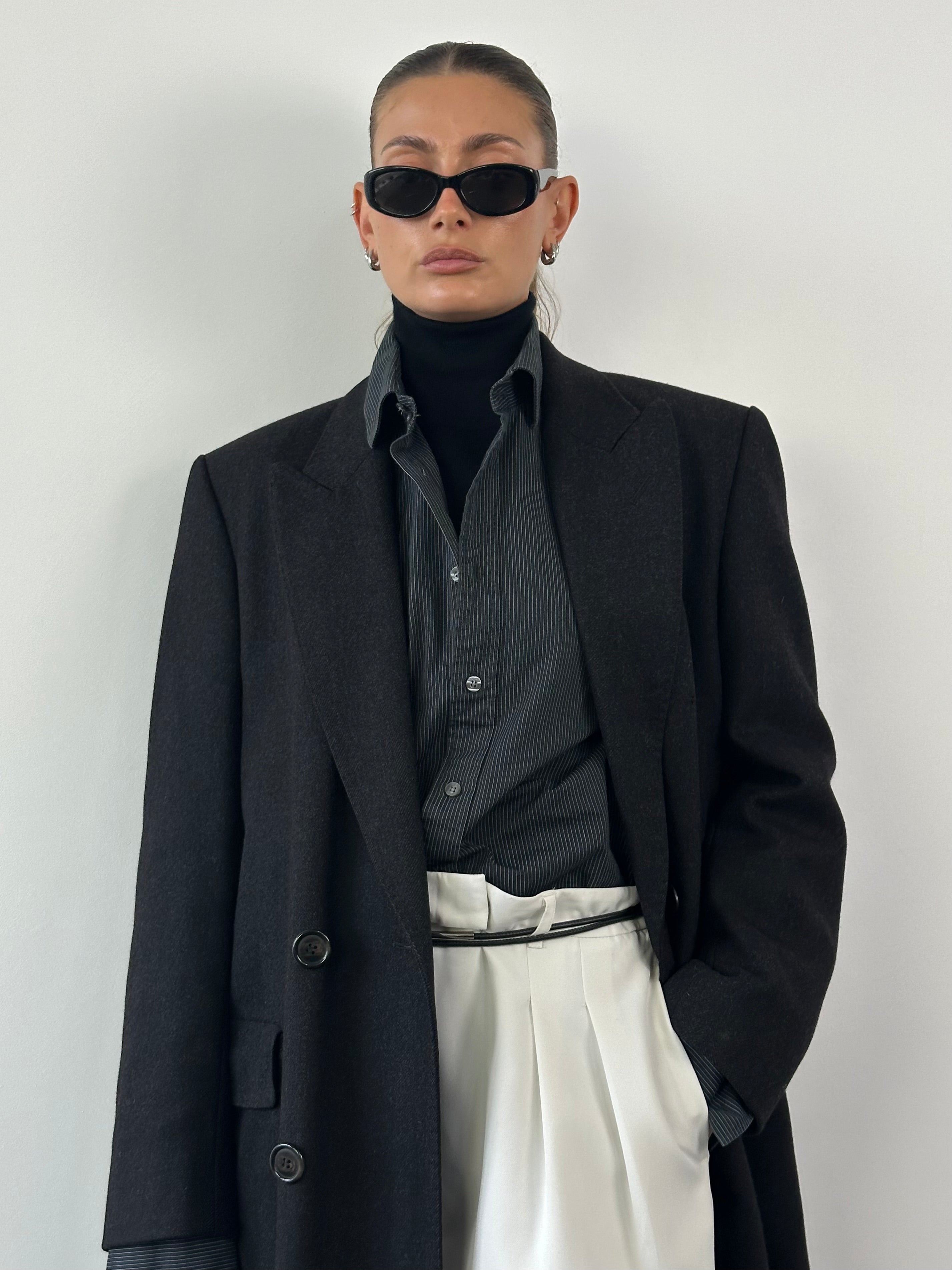 Christian Dior pure wool double-breasted coat in size L/XL, shown hanging with tailored lapels and classic design, front view.