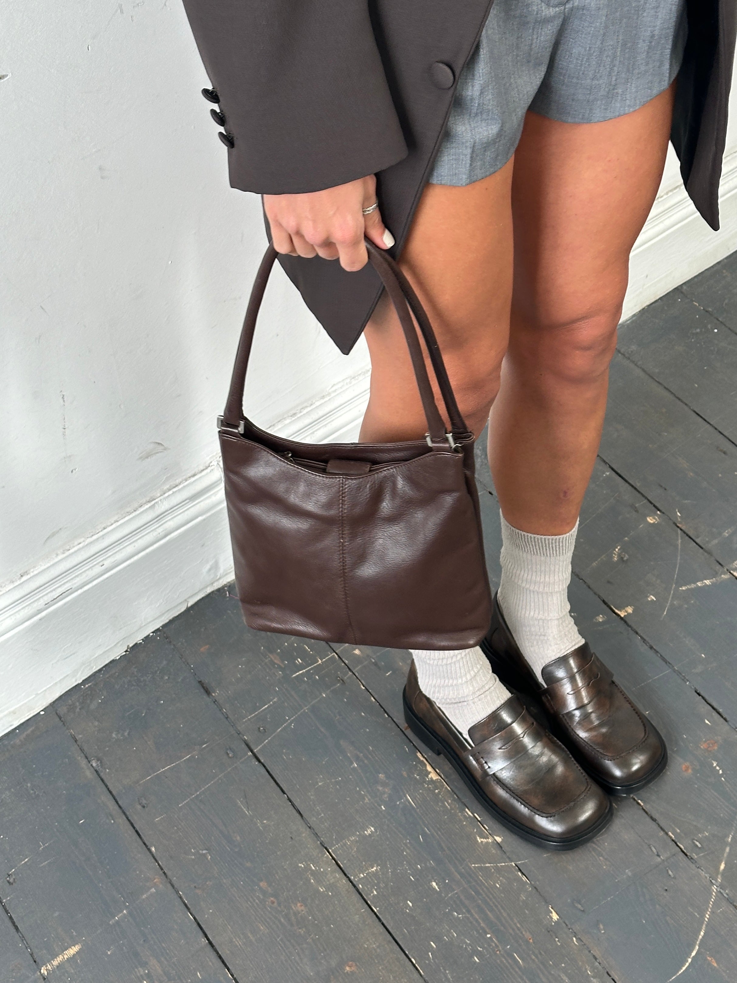 Vintage leather shoulder bag with adjustable strap and classic design, showcasing aged brown leather and detailed stitching.