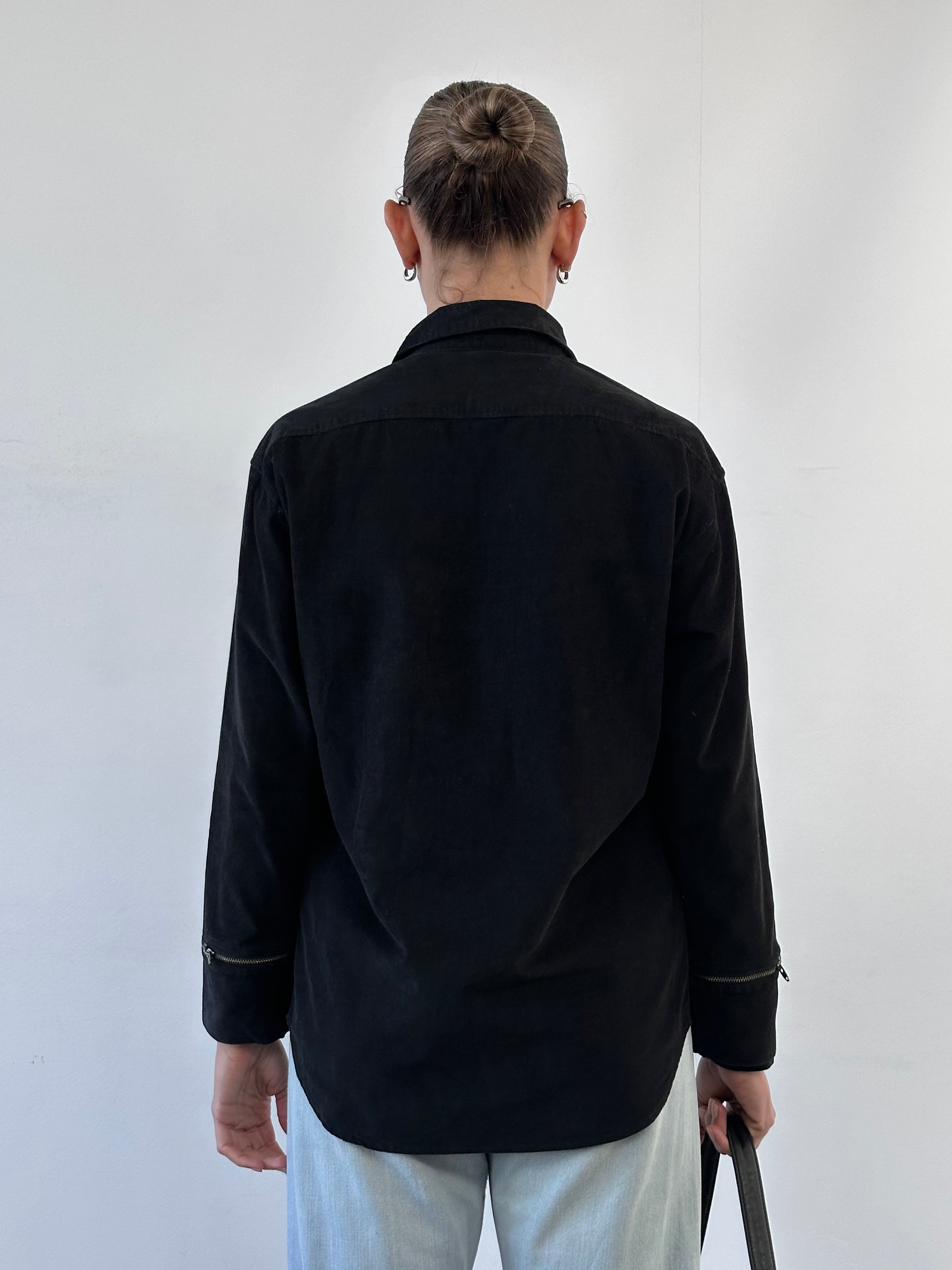 Versace Versus 00s corduroy zip shirt in black, featuring a classic collar and front zipper, displayed on a hanger.