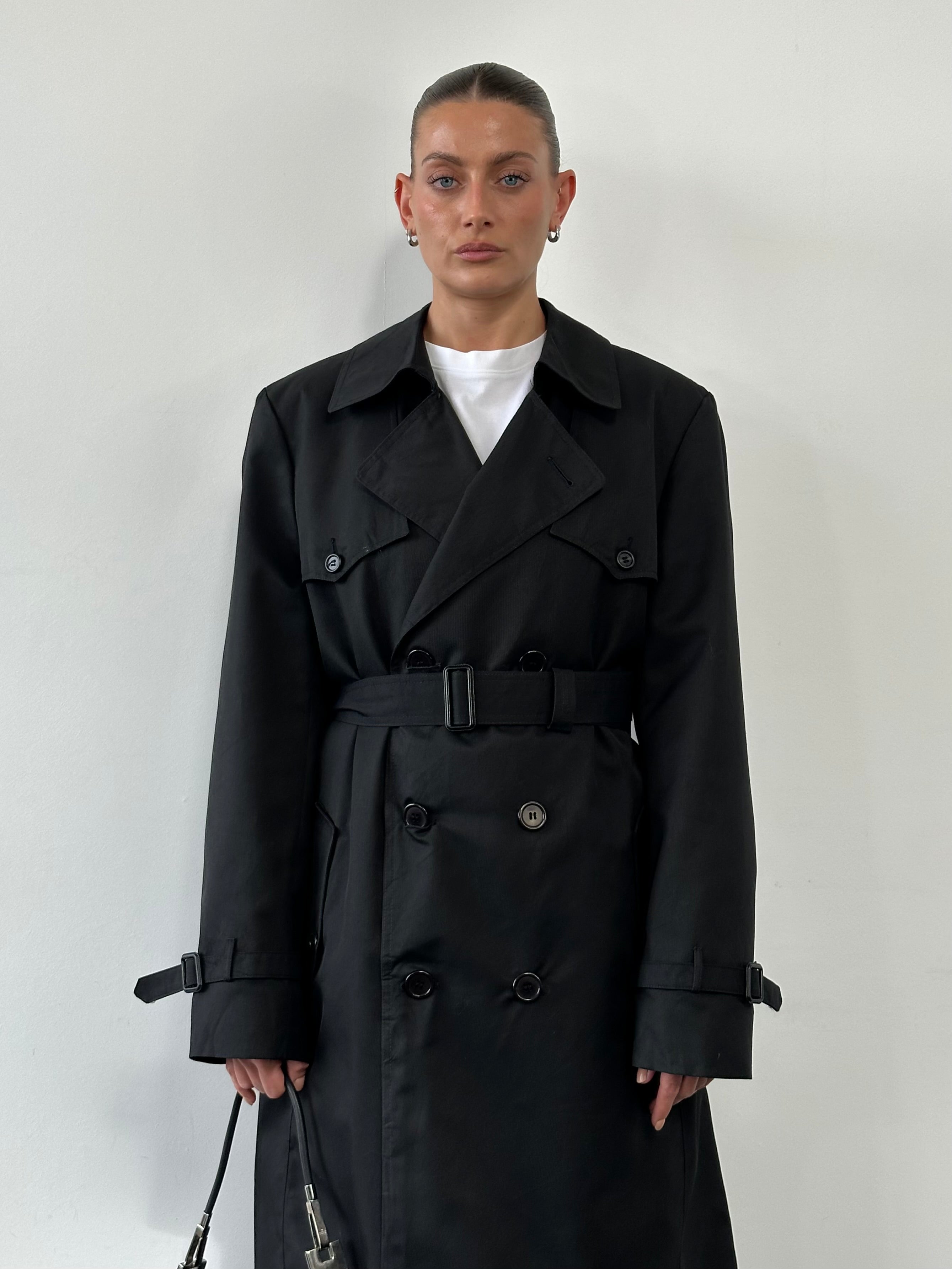 Christian Dior Monsieur double-breasted trench coat in XL, shown hanging on a wooden hanger, featuring classic design and beige fabric.