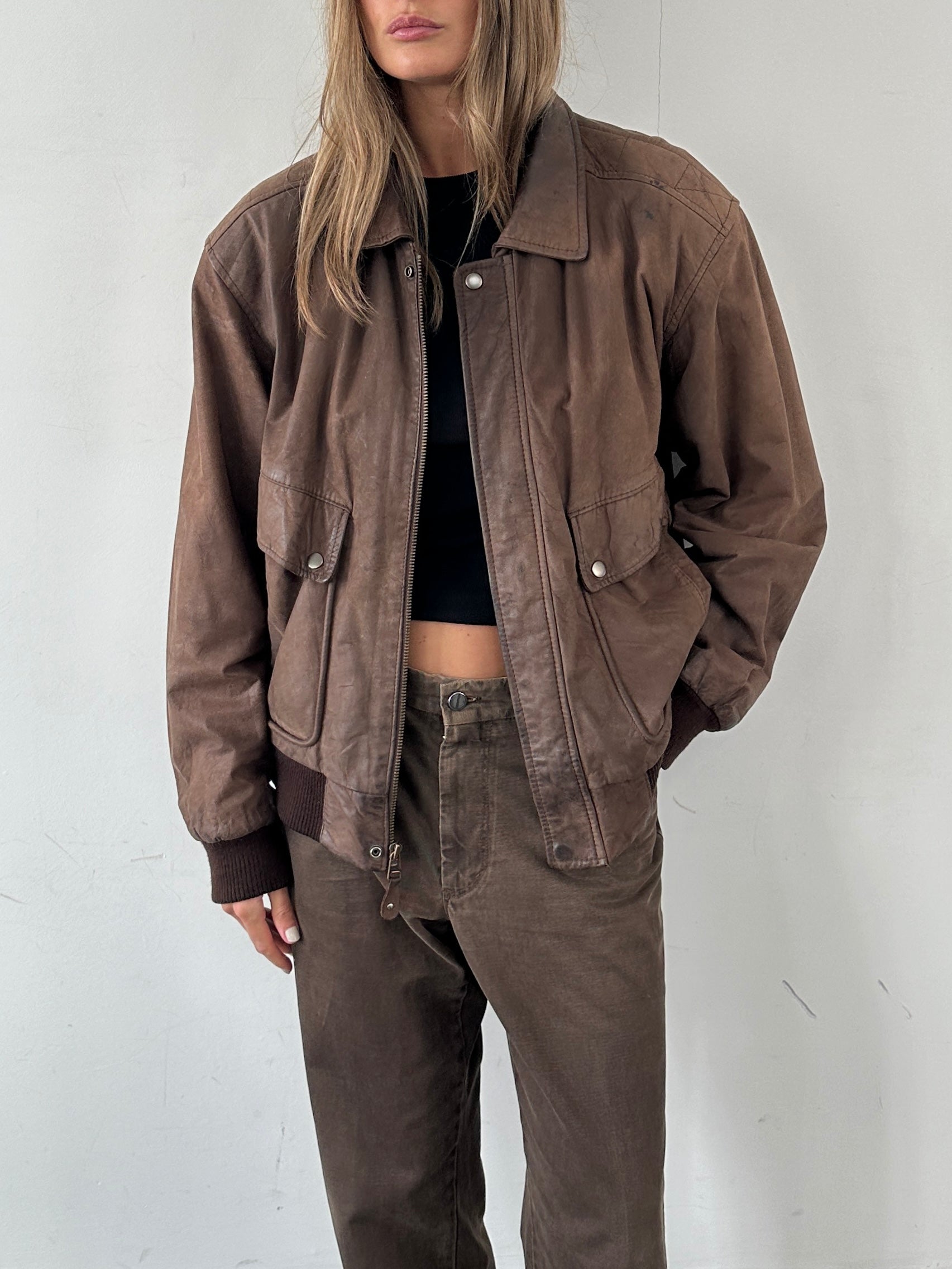 Vintage brand vintage leather bomber jacket, size large, featuring classic design with ribbed cuffs and collar, shown on a hanger.