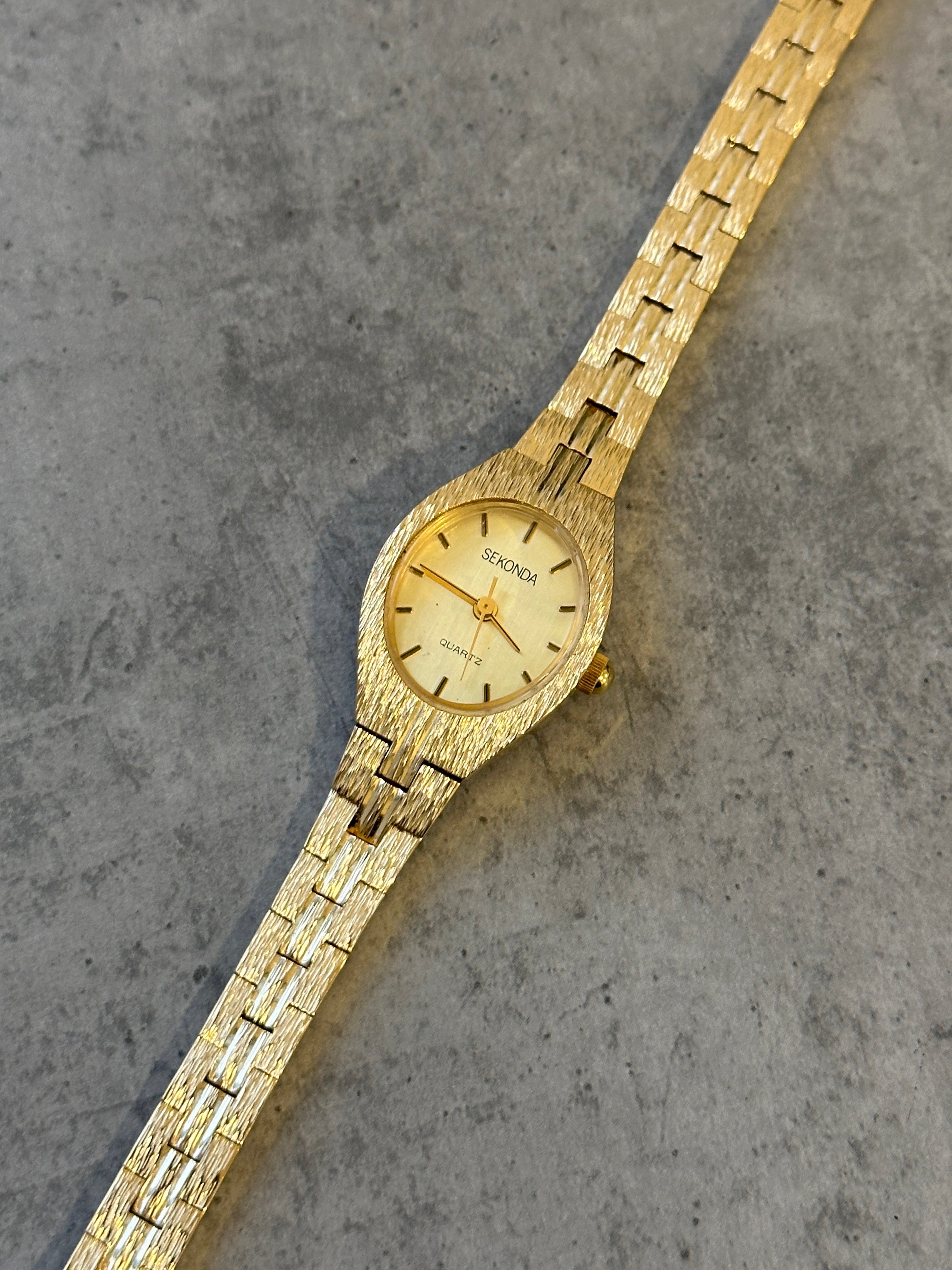 Sekonda 1990s gold-tone quartz watch with round dial and metal bracelet, vintage style timepiece.