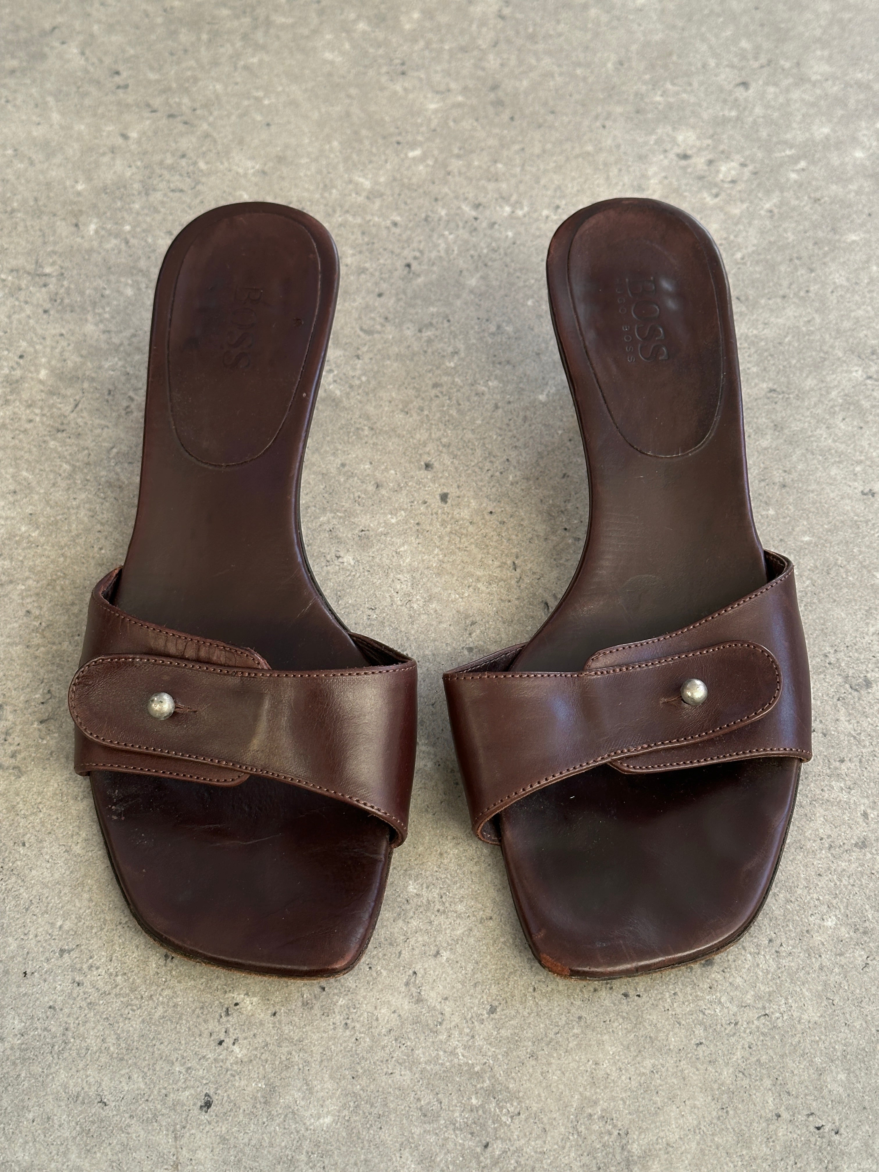 Hugo Boss leather mules in UK size 5, EUR 38, with sleek design and pointed toe, displayed on a neutral background.