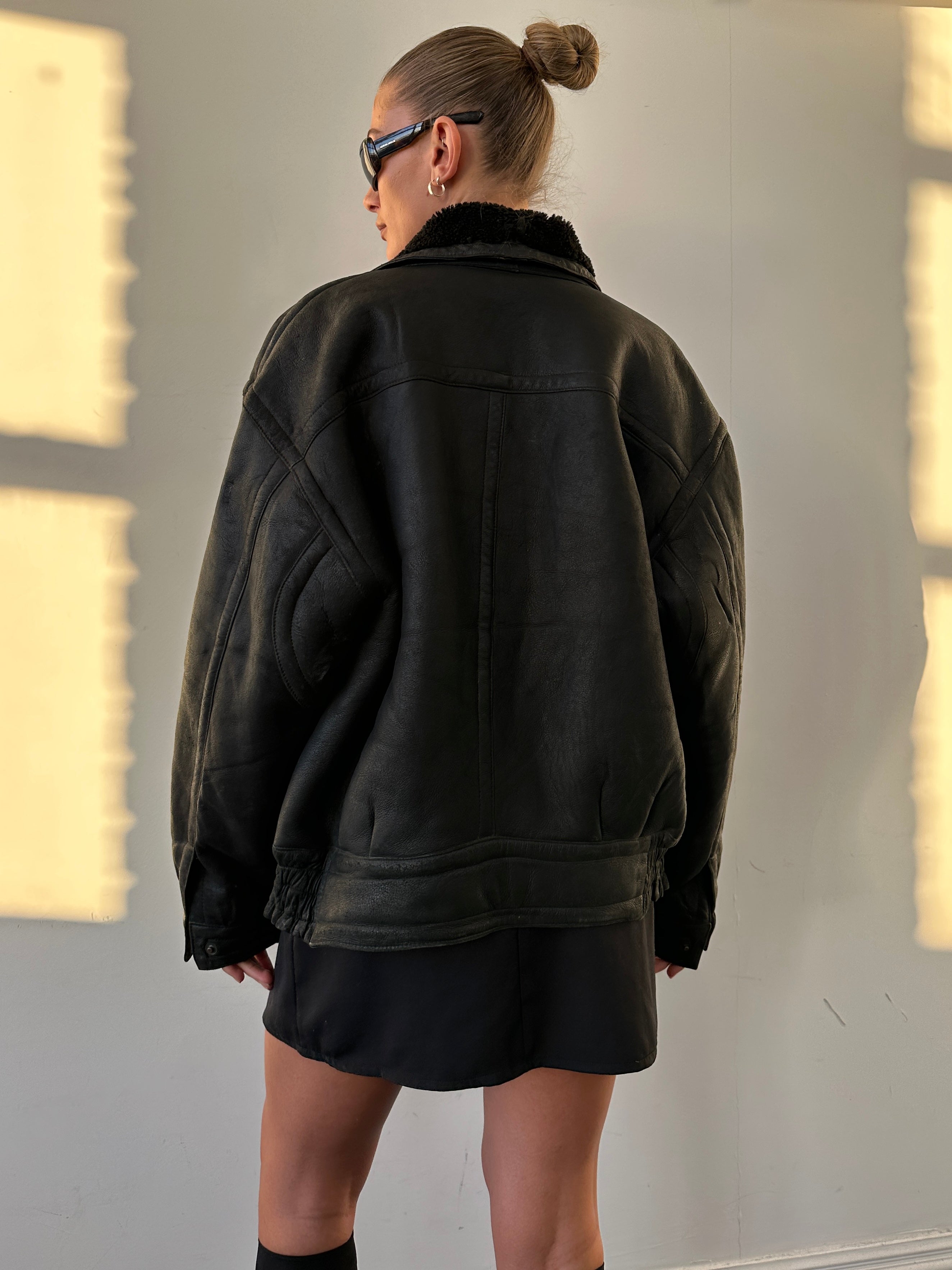 Vintage shearling leather jacket in size M/L, featuring classic design and textured fur collar visible on the brown leather exterior.