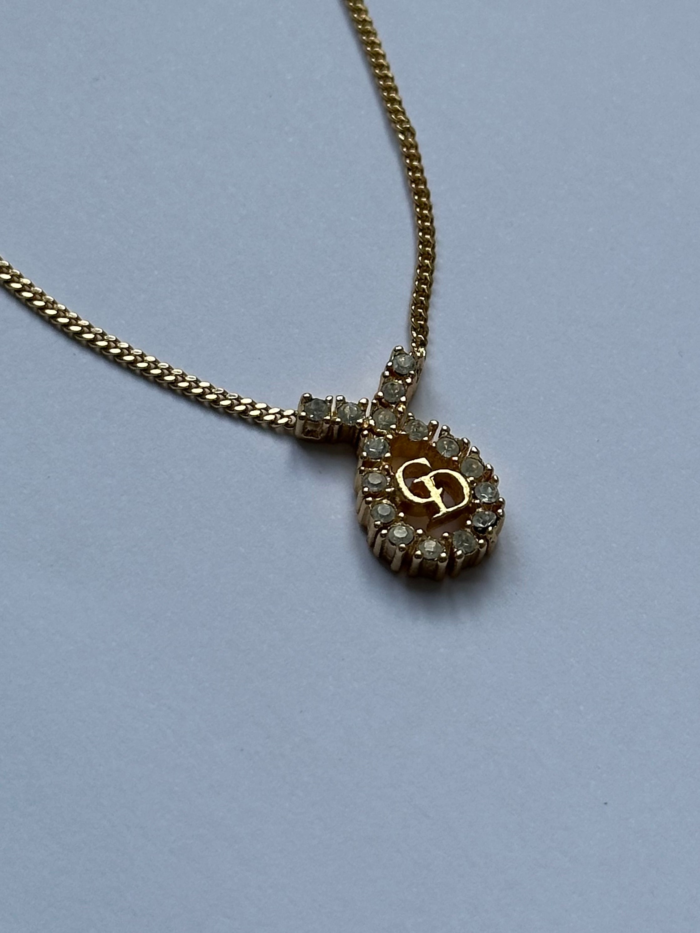 Christian Dior 16-inch gold plated rhinestone drop logo pendant necklace, featuring a sparkling Dior emblem.