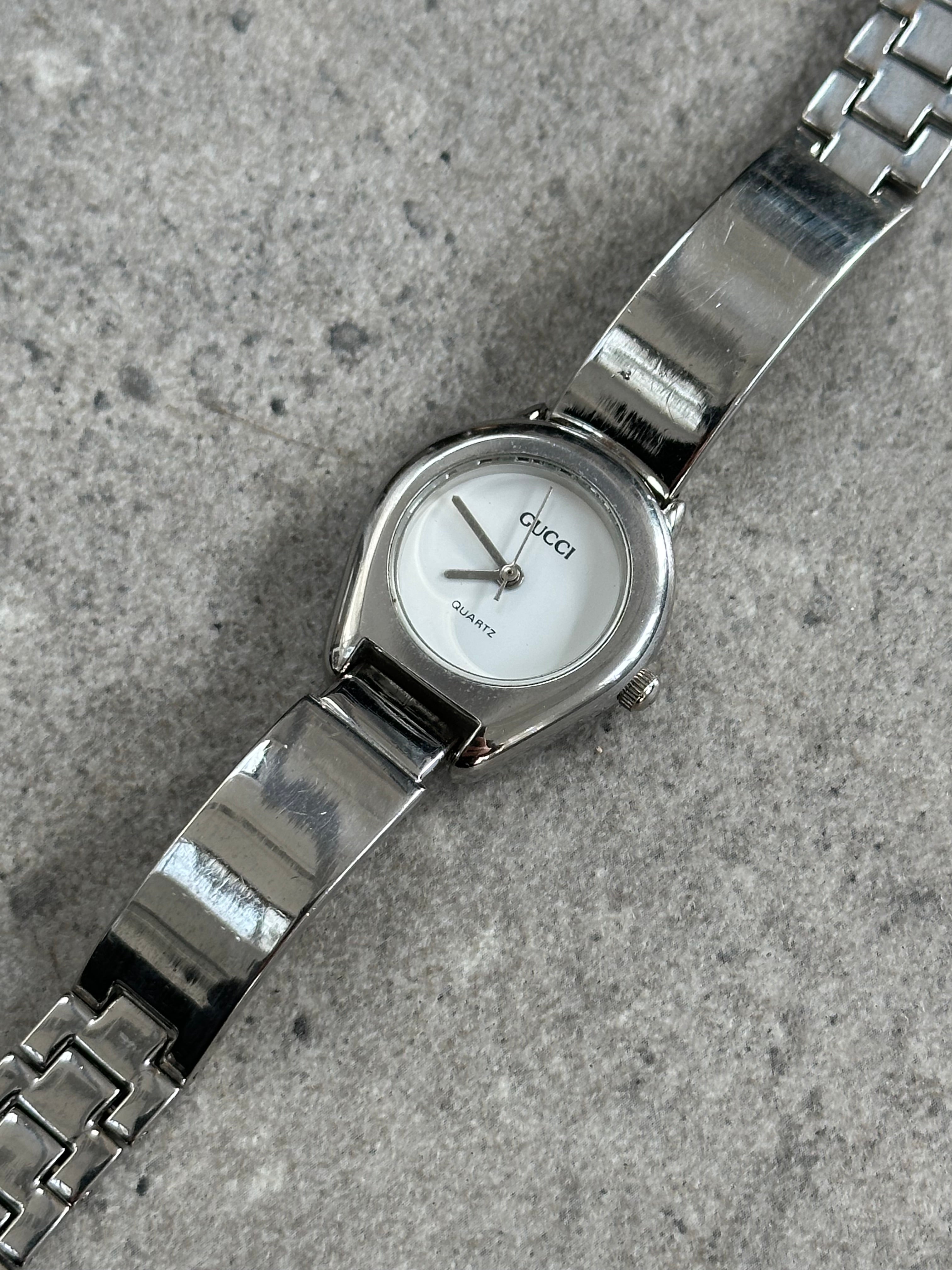 Gucci 1990s stainless steel quartz watch with sleek design and silver-tone dial, featuring the Gucci logo and classic style.