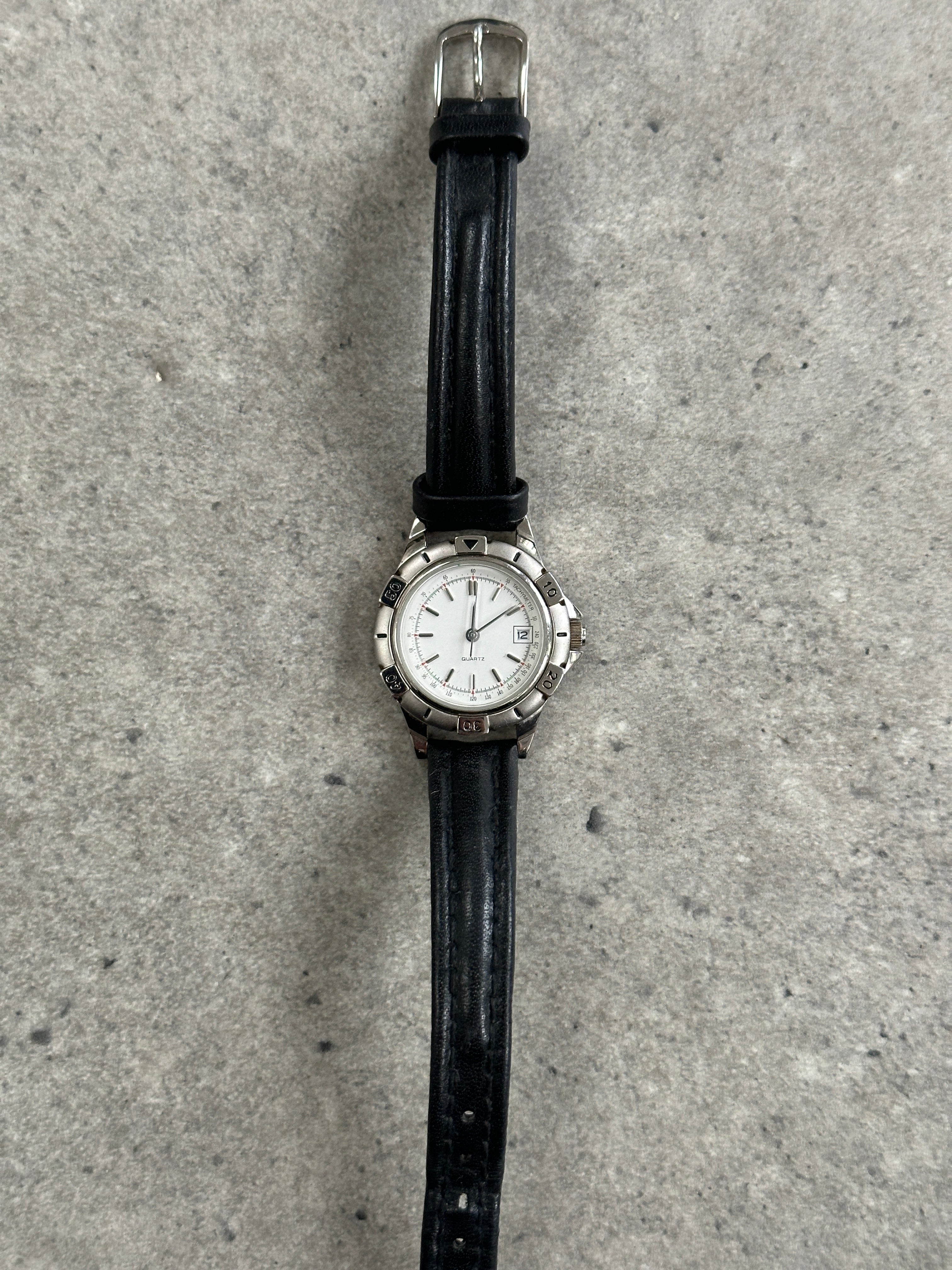 Vintage 1990s silver tone round quartz watch with Japan movement, classic design and analog display.