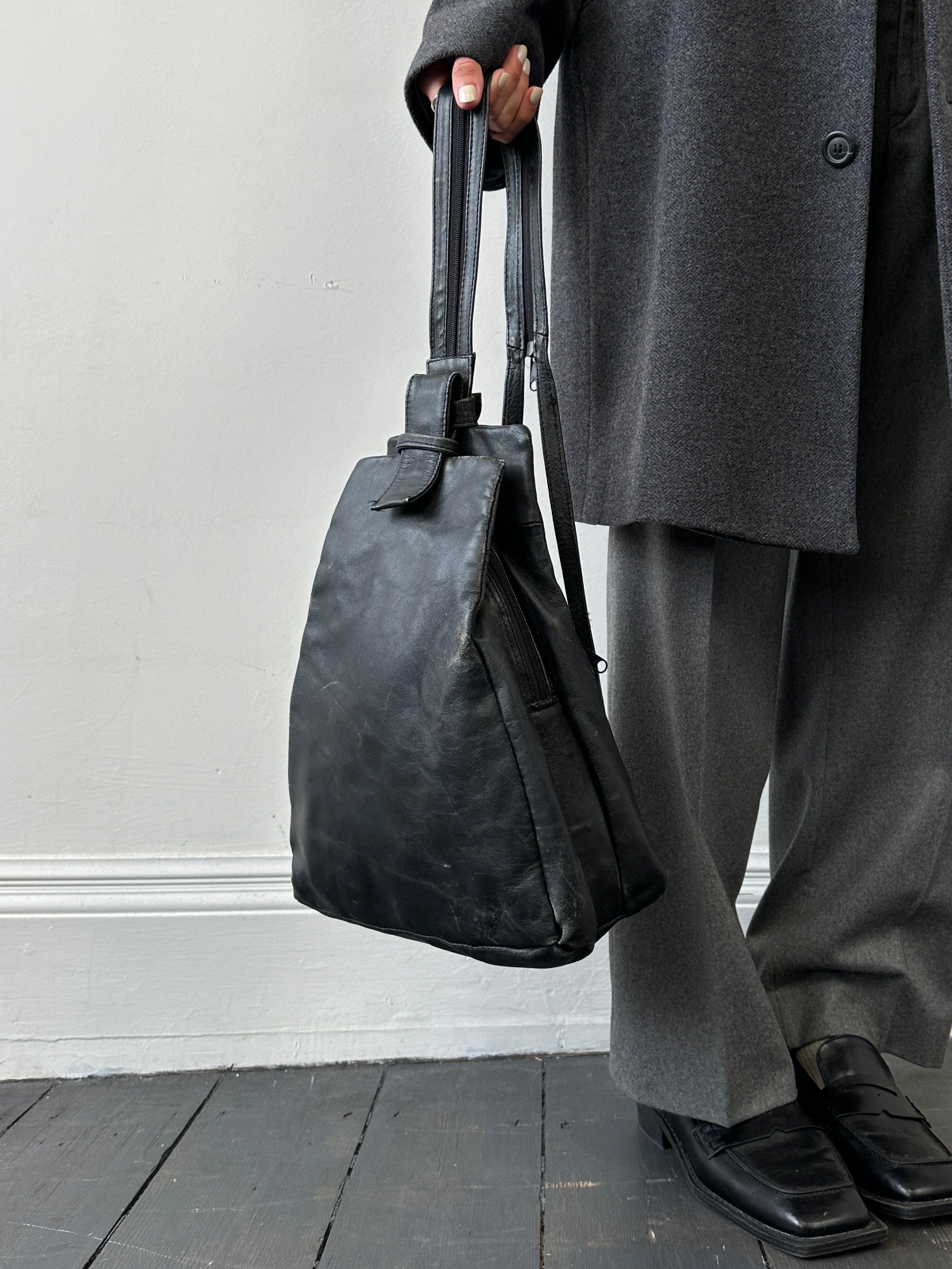 Vintage distressed faux leather rucksack crossbody bag with adjustable strap and vintage-style hardware, front pocket, and rugged design.