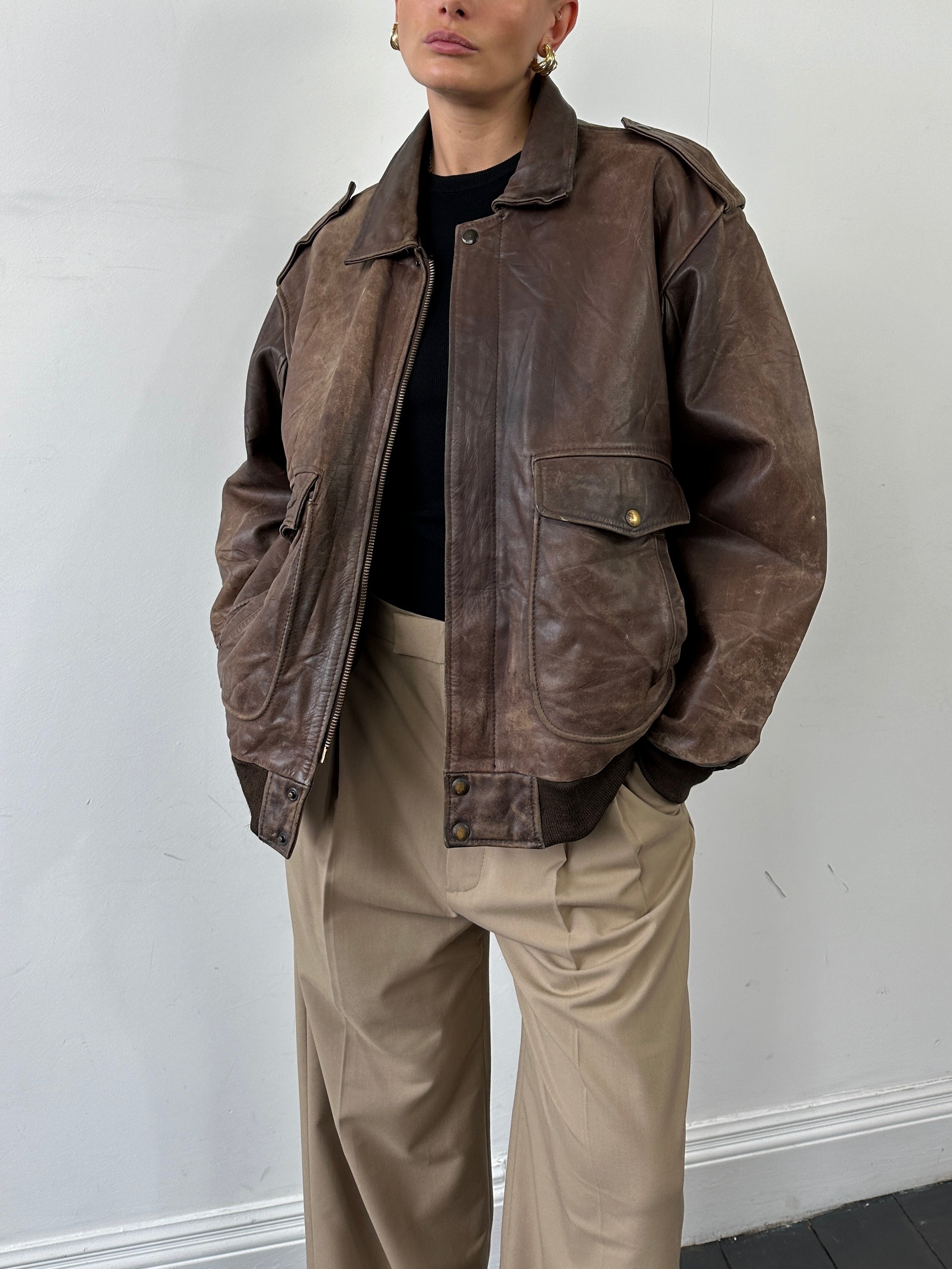 Vintage distressed leather bomber jacket in XL size, featuring rugged texture and classic style.
