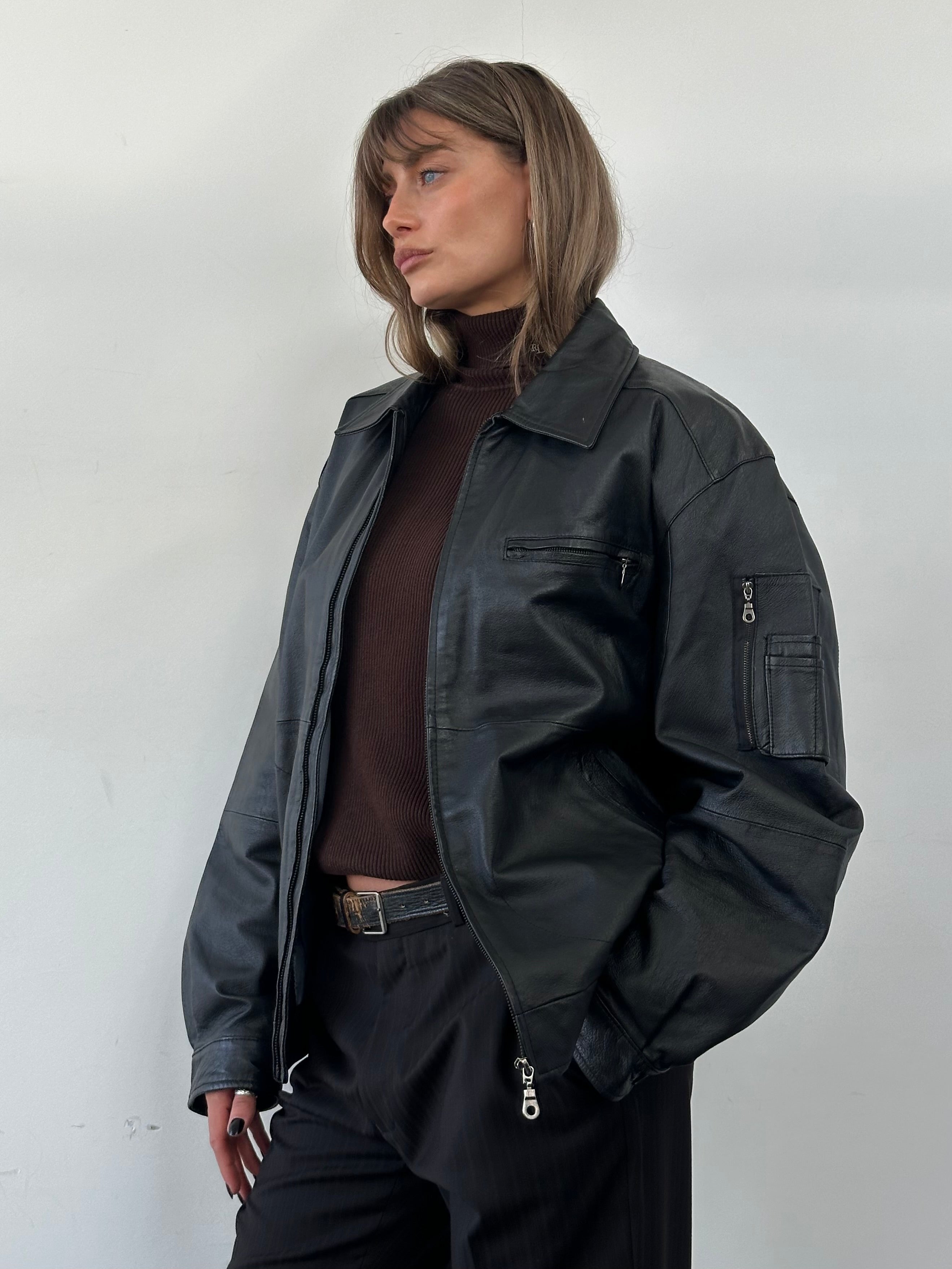Vintage leather bomber jacket in XL size featuring classic design and rich brown color, displayed on a hanger.