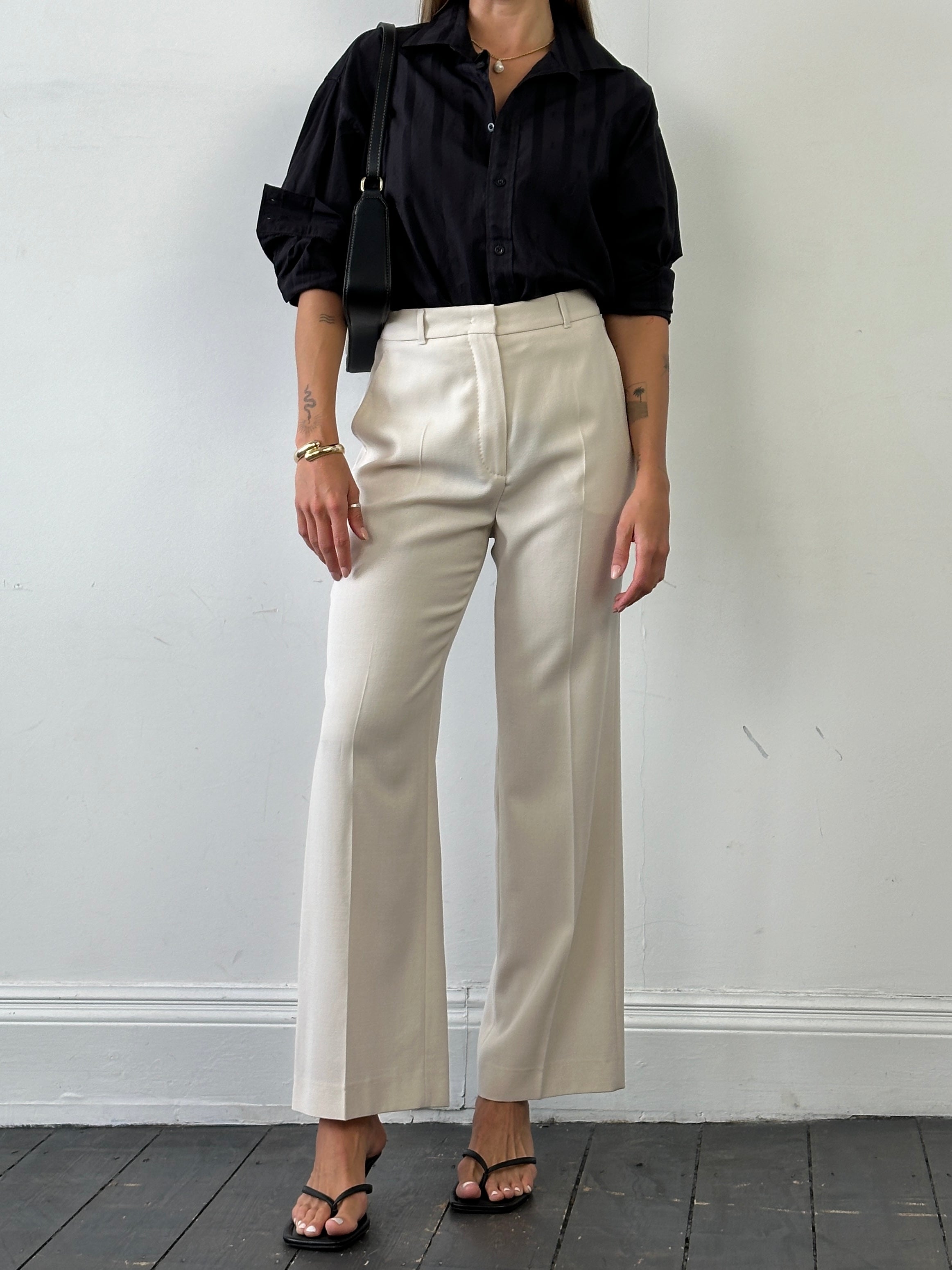 Max Mara high-waisted tailored wool trousers in a neutral color, displayed on a flat lay with detailed stitching and waistband.